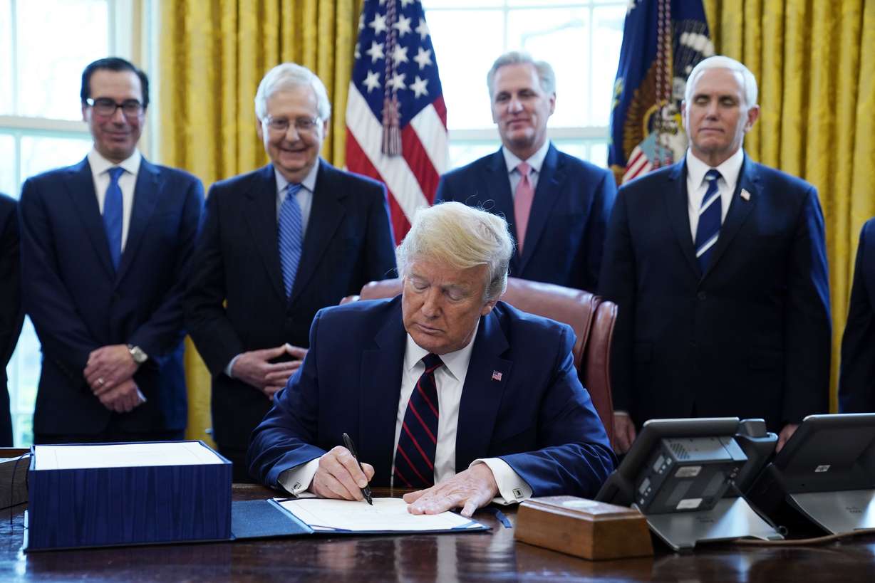 President Donald Trump signs the coronavirus stimulus relief package, at the White House in Washington, on March 27, 2020, accompanied by, from left, Treasury Secretary Steven Mnuchin, Senate Majority Leader Mitch McConnell of Ky., House Minority Kevin McCarthy of Calif., and Vice President Mike Pence.