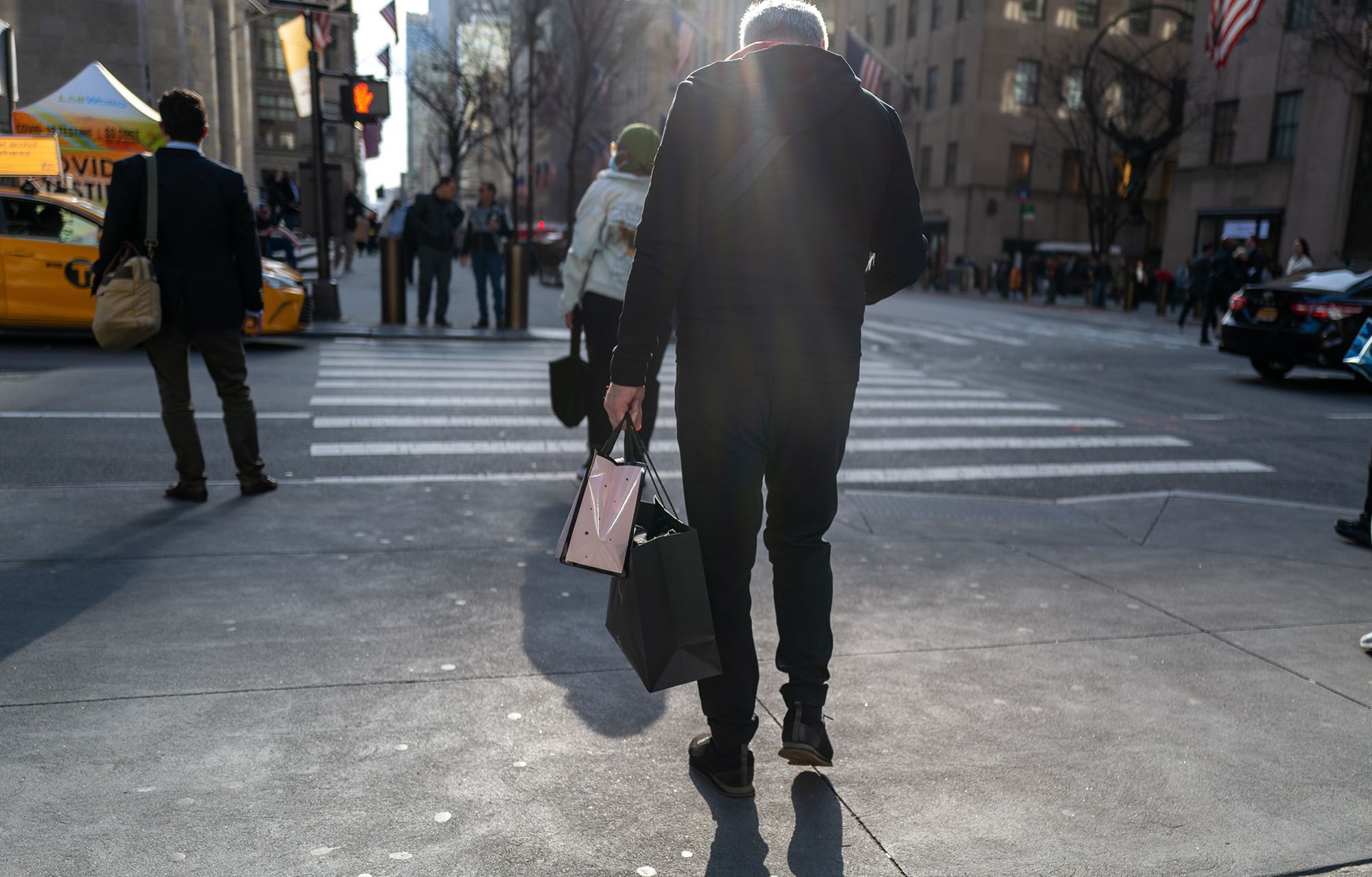 People walk along 5th Avenue in Manhattan, one of the nation's premier shopping streets, on Feb. 15 in New York City. Baby Boomers are living it up, splurging on cruises and restaurants. Younger Americans are struggling just to keep up.