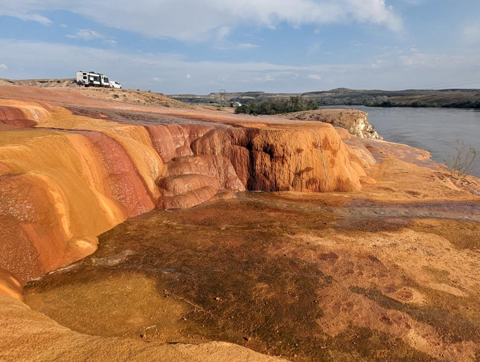 Orange travertine glistens in the sun, as water from Crystal Geyser trickles into the Green River.
