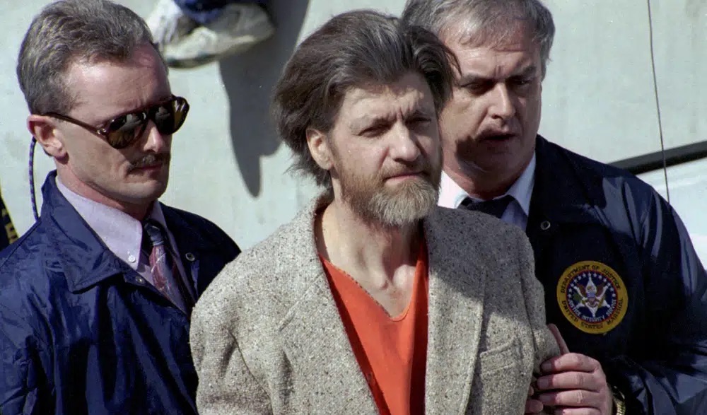 Theodore Kaczynski is flanked by federal agents as he is led to a car from the federal courthouse in Helena, Mont., April 4, 1996. Kaczynski, known as the “Unabomber,” died by suicide, sources said Sunday.