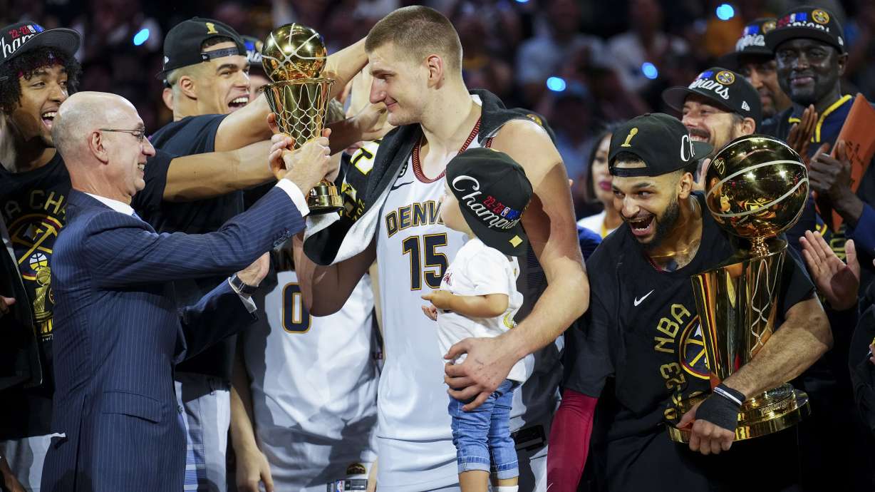 Commissioner Adam Silver, left, hands the MVP award to Denver Nuggets center Nikola Jokic, center, after the team won the NBA Championship with a victory over the Miami Heat in Game 5 of basketball's NBA Finals, Monday, June 12, 2023, in Denver.