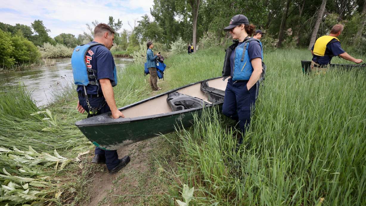 Firefighters retrieve a canoe after several children and two adults fell into the Jordan River when a pair of canoes capsized on Tuesday.