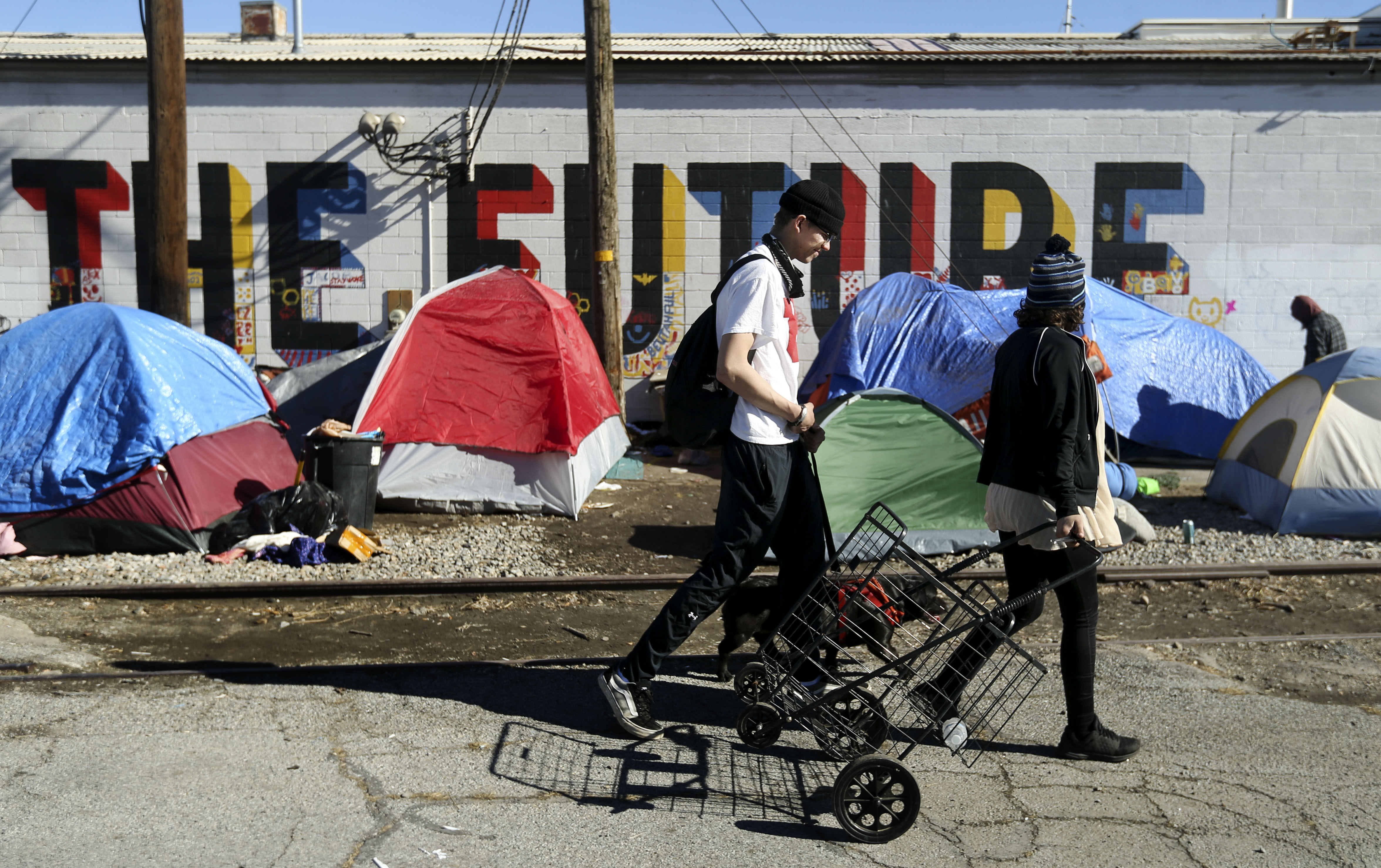 People walk past a homeless encampment on 400 West in Salt Lake City on Feb. 7, 2021. City, county and state officials in Utah are considering creating a sanctioned homeless campground, likely in Salt Lake City.