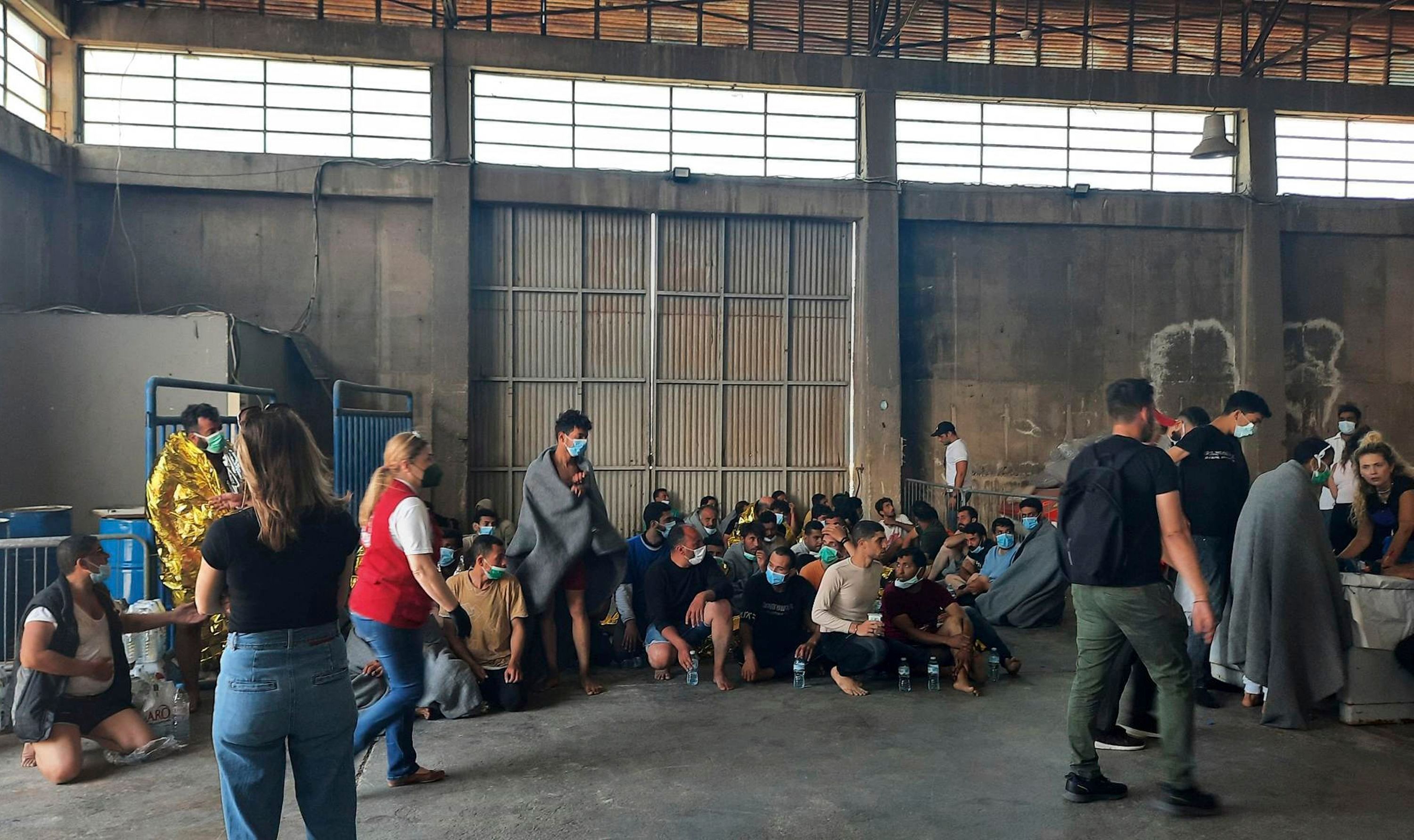 Survivors sit in a warehouse at the port in Kalamata town on Wednesday. At least 79 people died after a migrant boat carrying hundreds of people sank off the Greek coast. 