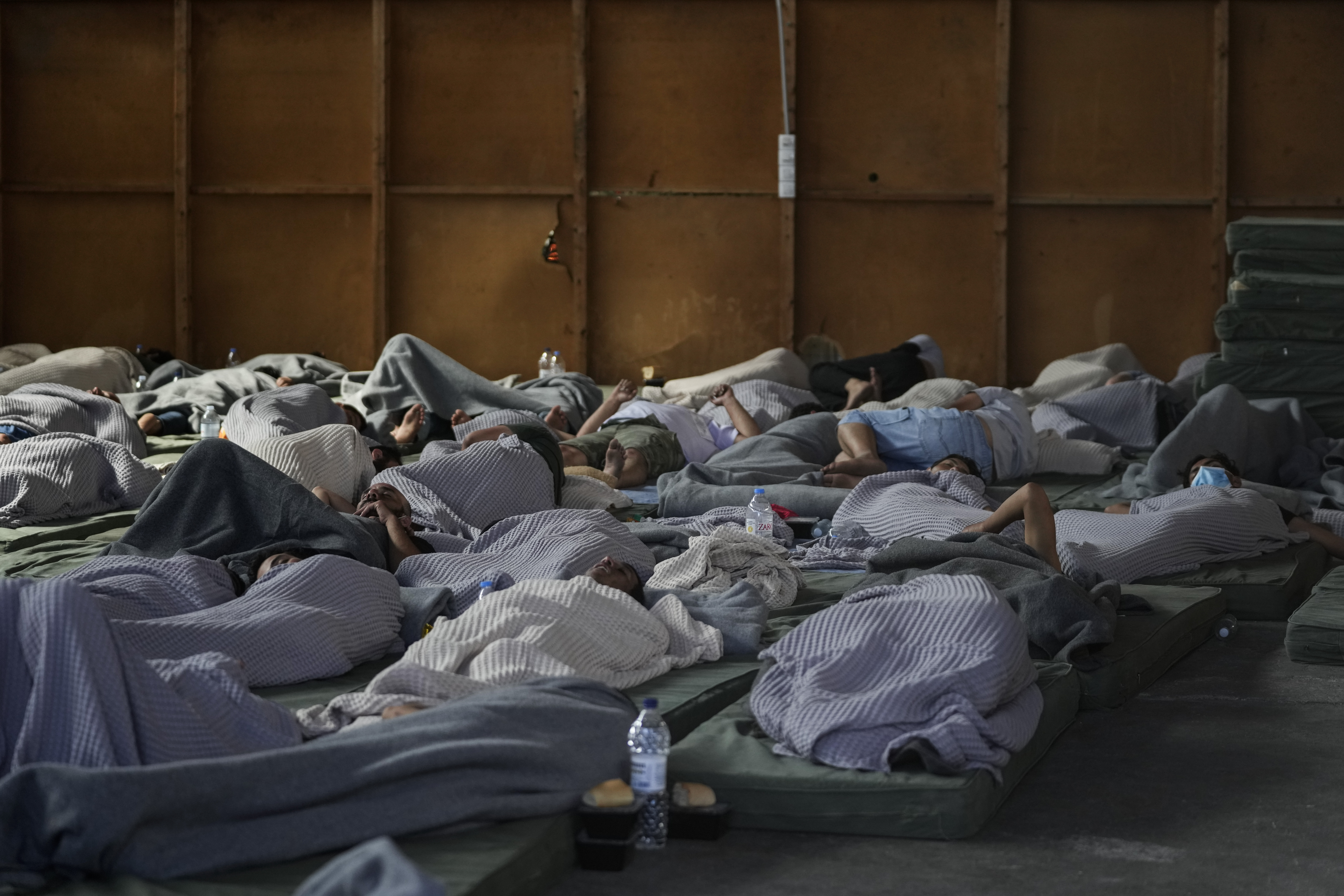 Survivors of a shipwreck sleep at a warehouse at the port in Kalamata town, about 150 miles southwest of Athens, Wednesday. A fishing boat carrying migrants capsized and sank off the coast of Greece on Wednesday, authorities said, leaving at least 78 people dead and many dozens feared missing in one of the worst disasters of its kind this year.