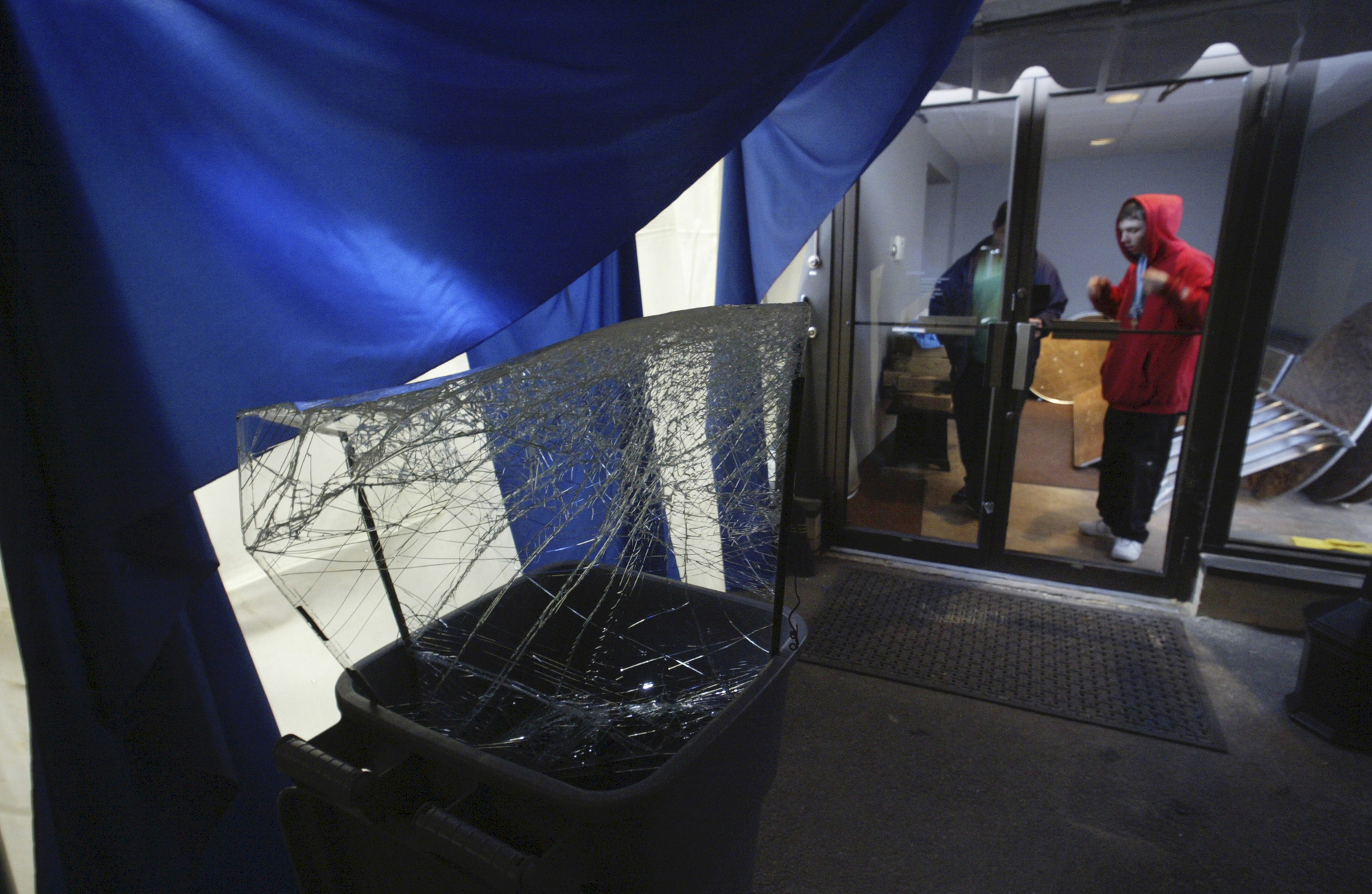 FILE - Nick Sopchak, right, looks at broken glass from a rear door of the Everhart Museum, Friday, Nov. 18, 2005, in Scranton, Pa. Federal authorities announced charges against a ring of nine people for thefts of millions of dollars worth of paintings, sports memorabilia and other valuables. The thefts took place over more than two decades at 20 different museums and institutions across Pennsylvania, New Jersey, New York and North Dakota, the U.S. Attorney for the Middle District of Pennsylvania said Thursday, June 15, 2023. 