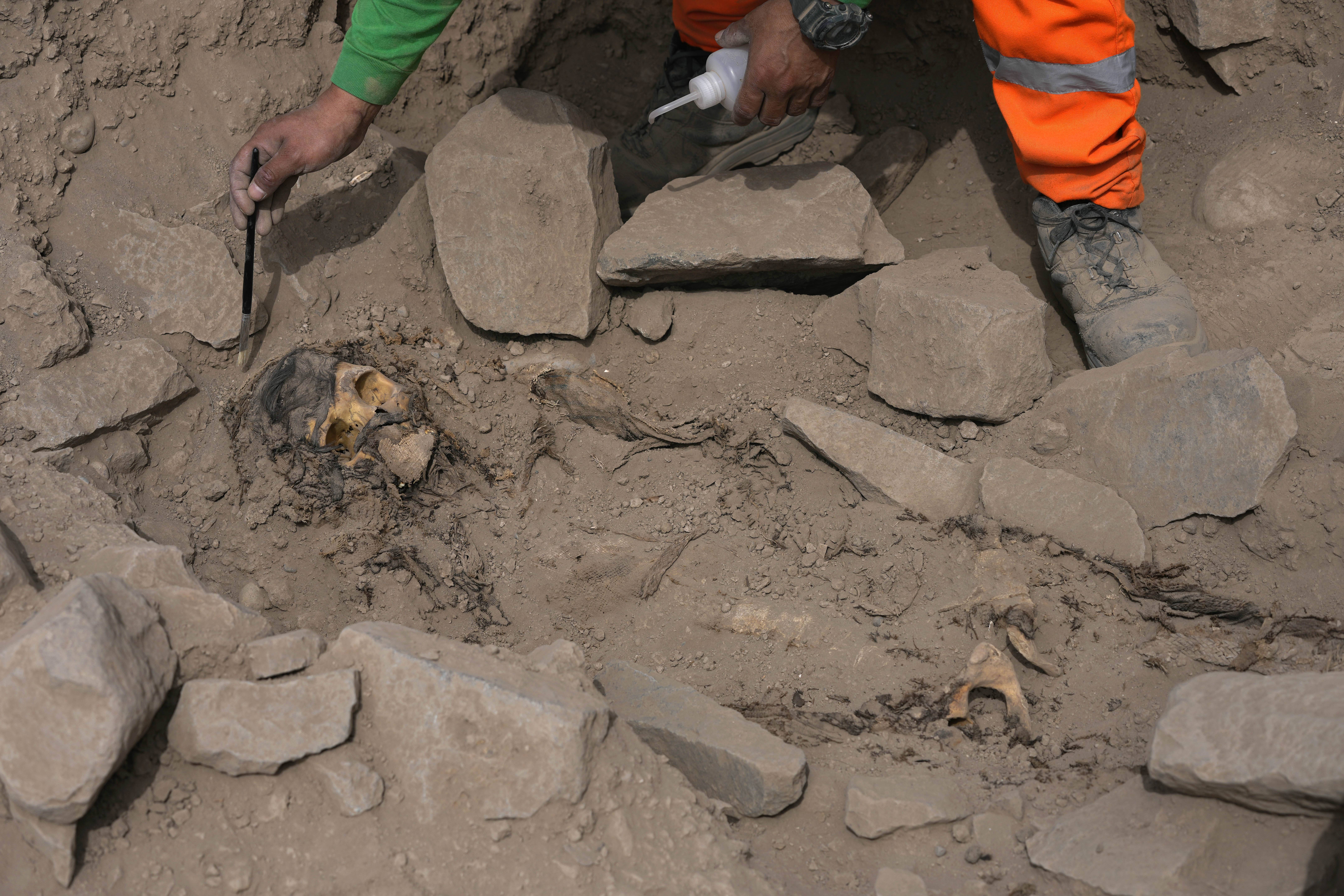 An archaeologist excavates a pre-Hispanic mummy that was discovered next to a training field for a Peruvian professional soccer team in the El Rimac neighborhood of Lima, Peru, Thursday. 