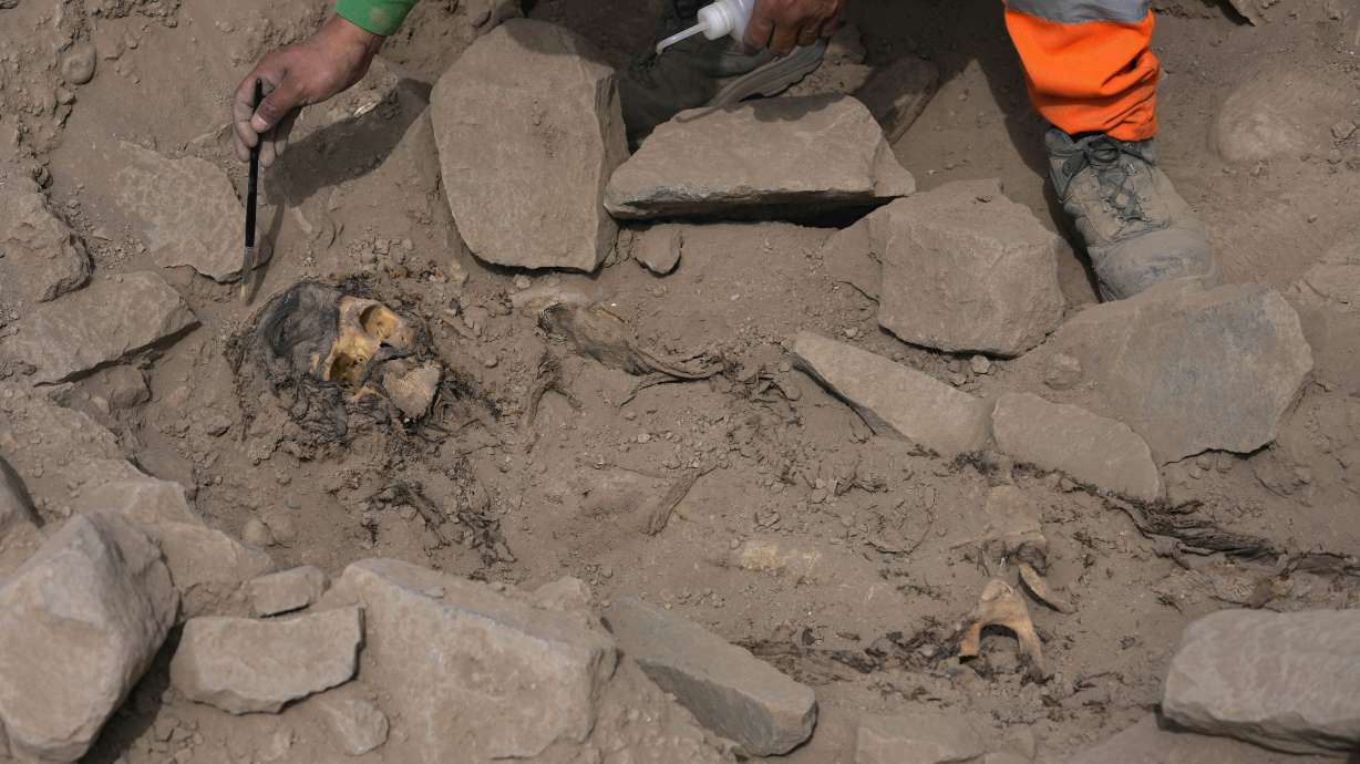 An archaeologist excavates a pre-Hispanic mummy that was discovered next to a training field for a Peruvian professional soccer team in the El Rimac neighborhood of Lima, Peru, Thursday.