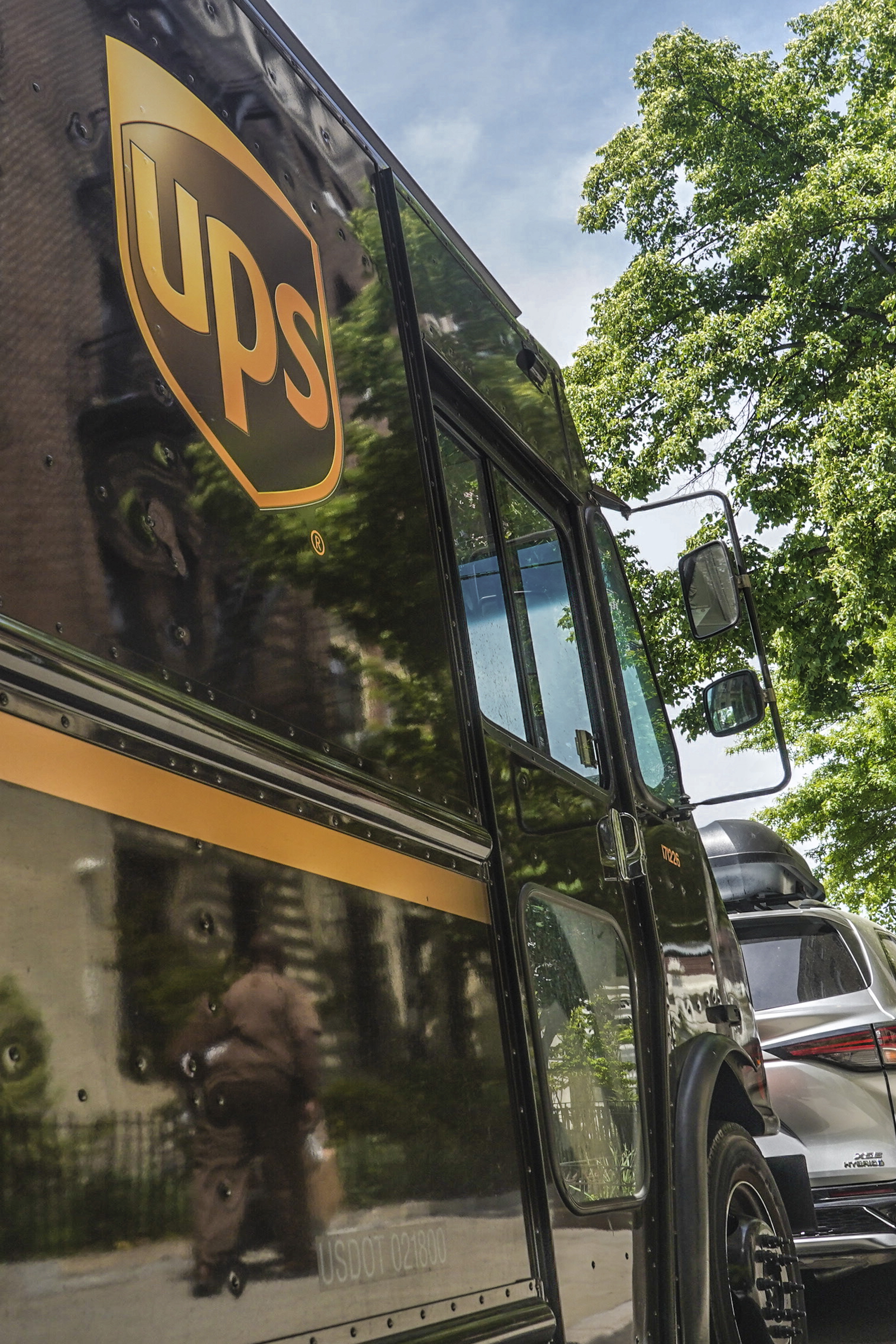 A UPS delivery driver wheeling a load of boxes is reflected on the truck on May 12, in New York. UPS workers say they are prepared to strike if the company does not meet their demands before the end of the current contract on July 31. 