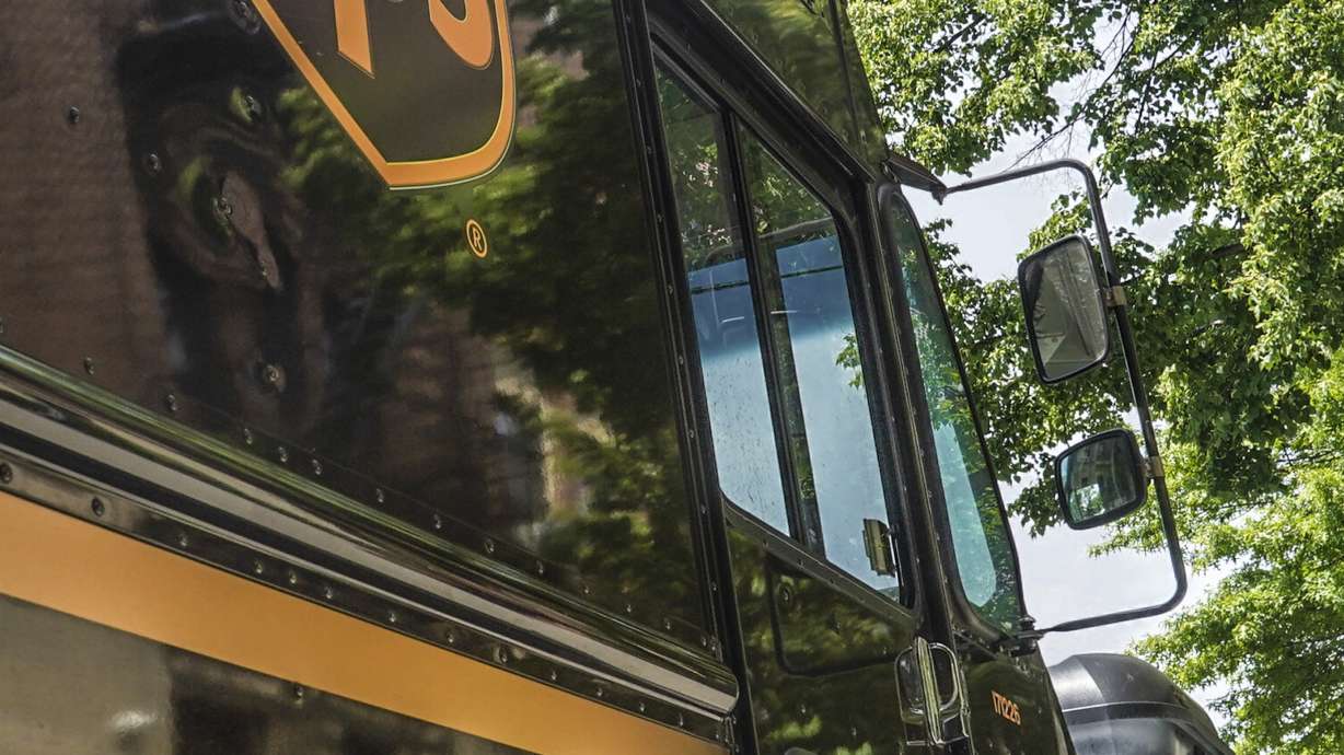 A UPS delivery driver wheeling a load of boxes is reflected on the truck on May 12, in New York. UPS workers say they are prepared to strike if the company does not meet their demands before the end of the current contract on July 31.