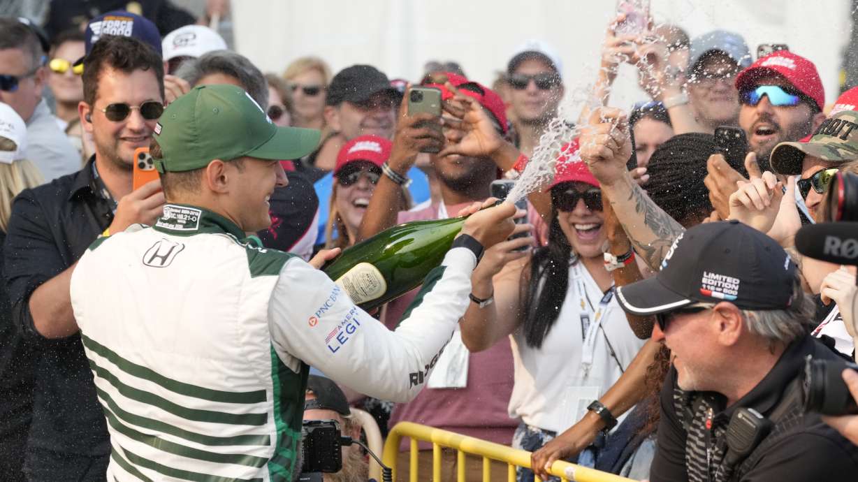 Alex Palou, front left, sprays fans after winning the IndyCar Detroit Grand Prix auto race, Sunday, June 4, 2023, in Detroit.