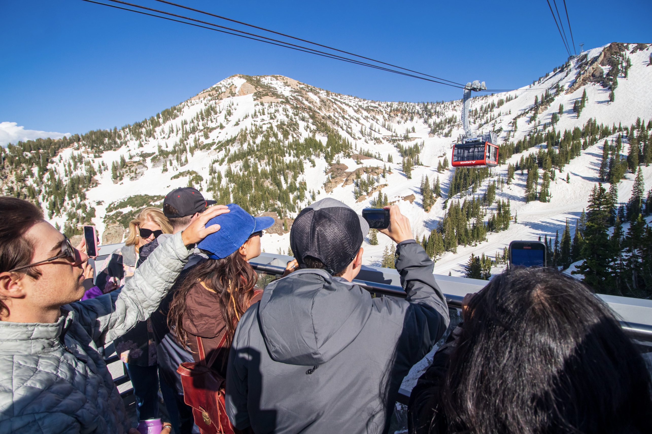 Members of the media, social media influencers and tourism experts take photos from the outdoor balcony of the Snowbird tram during a preview Friday evening.