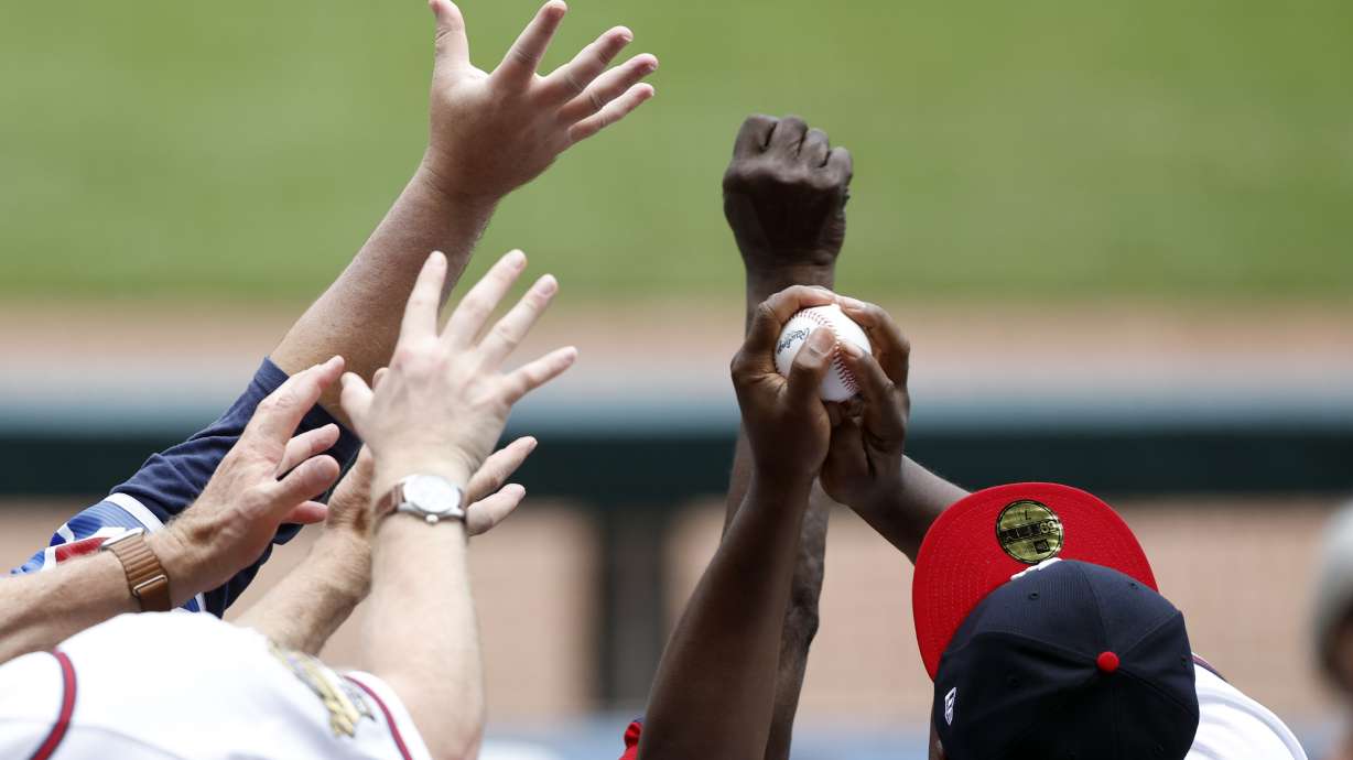 A fan catches a ball thrown into the stands in the sixth inning of a baseball game between the Colorado Rockies and the Atlanta Braves, Sunday, June 18, 2023, in Atlanta.