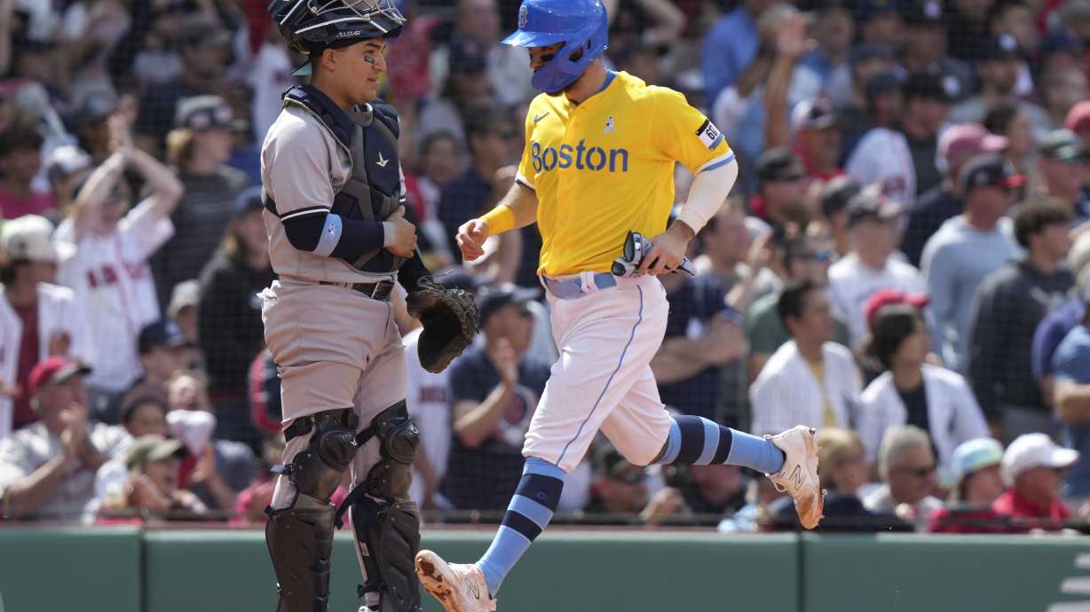 Boston Red Sox's Connor Wong, right, crosses home plate in front of New York Yankees' Jose Trevino, left, to score on a double by Red Sox's Alex Verdugo in the sixth inning of a baseball game, Sunday, June 18, 2023, in Boston.