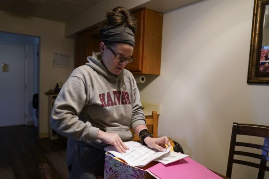 Samantha Richards looks over her Medicaid papers, June 9 in Bloomington, Ind. Richards has been on Medicaid her whole life and currently works two part-time jobs as a custodian.