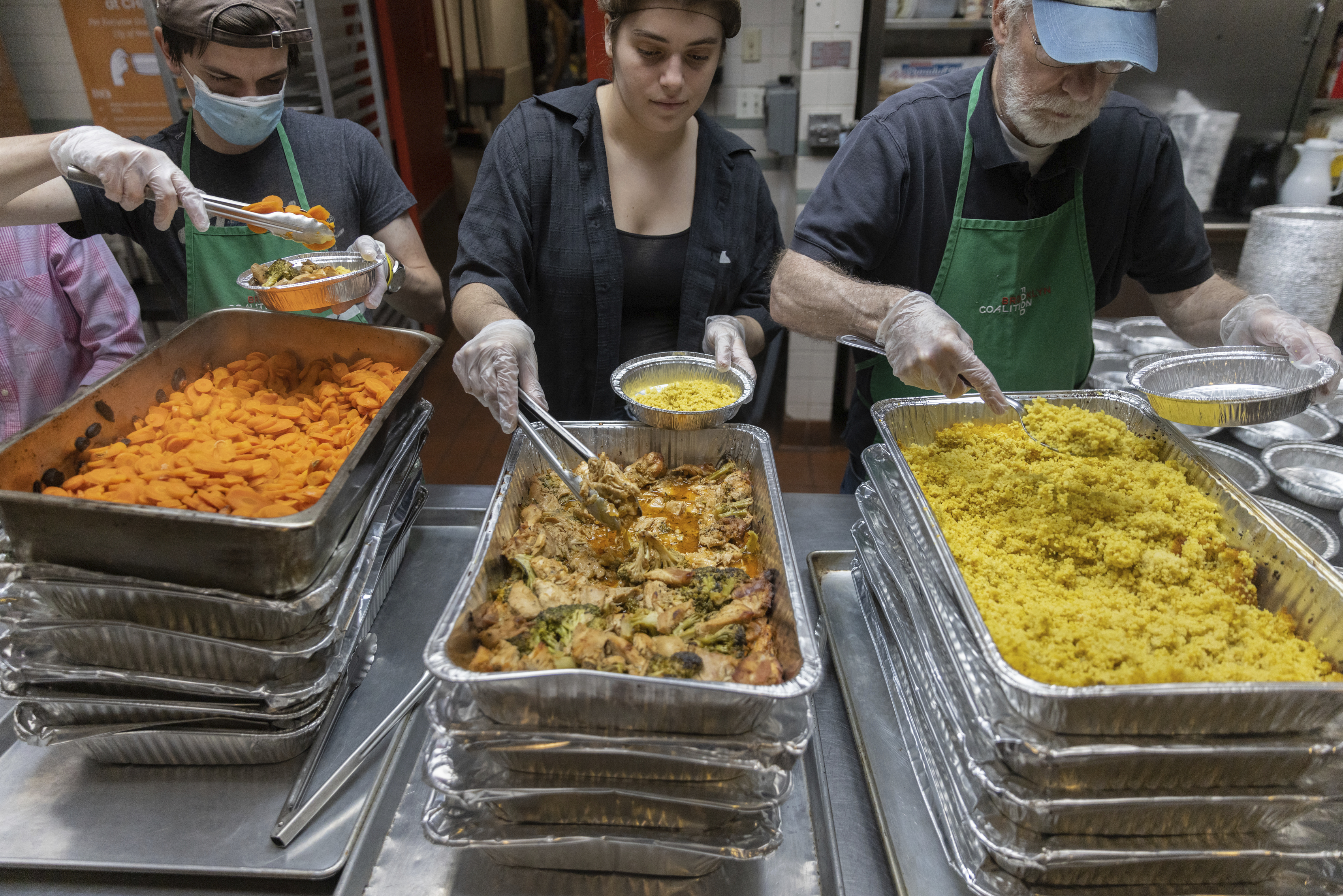 Nicholas Loud, left, Sophie Thurschwell, center, and Peter Woll prepare lunch boxes at Community Help in Park Slope, a soup kitchen and food pantry better known as CHiPS, on Friday in New York. Charitable giving in the United States declined in 2022. 