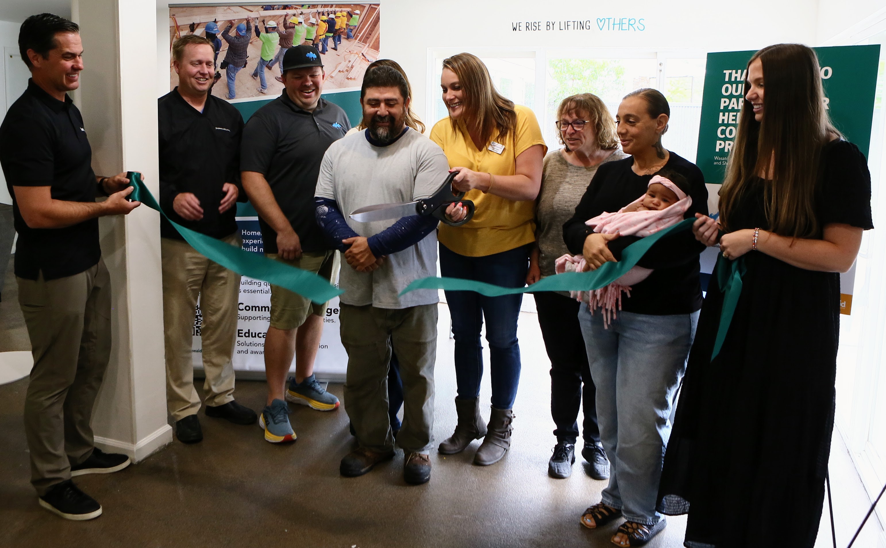Heidi Lund, executive director at LifeStart Village, helps others cut the ribbon on newly remodeled and repainted units at the nonprofit's Family Support Center on June 15.
