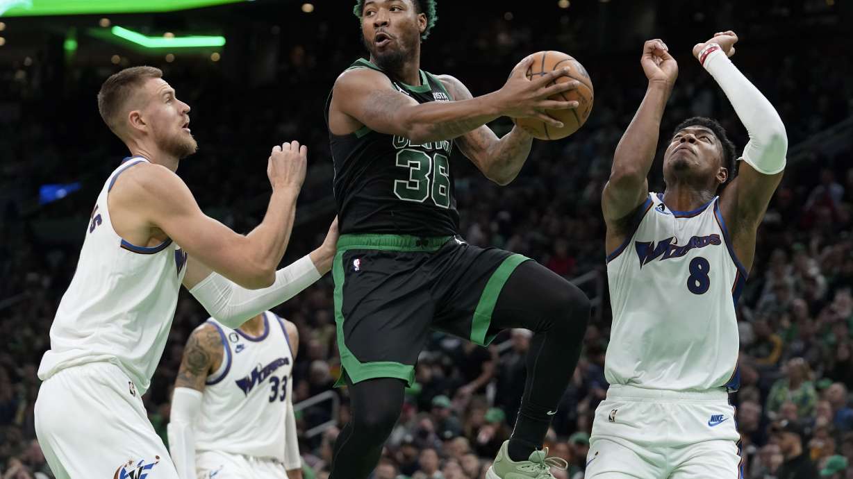 FILE - Boston Celtics guard Marcus Smart, center, looks to pass past Washington Wizards center Kristaps Porzingis, left, and forward Rui Hachimura, right, during the first half of an NBA basketball game Oct. 30, 2022, in Boston. A person with knowledge of the deal says the Wizards have agreed to trade Porzingis to the Celtics. The person spoke to The Associated Press on condition of anonymity because the agreement hadn’t been announced. The trade comes with Porzingis accepting his player option for next season. ESPN reports the deal also includes the Memphis Grizzlies who are acquiring Smart from Boston in exchange for first-round draft picks in 2023 and 2024.