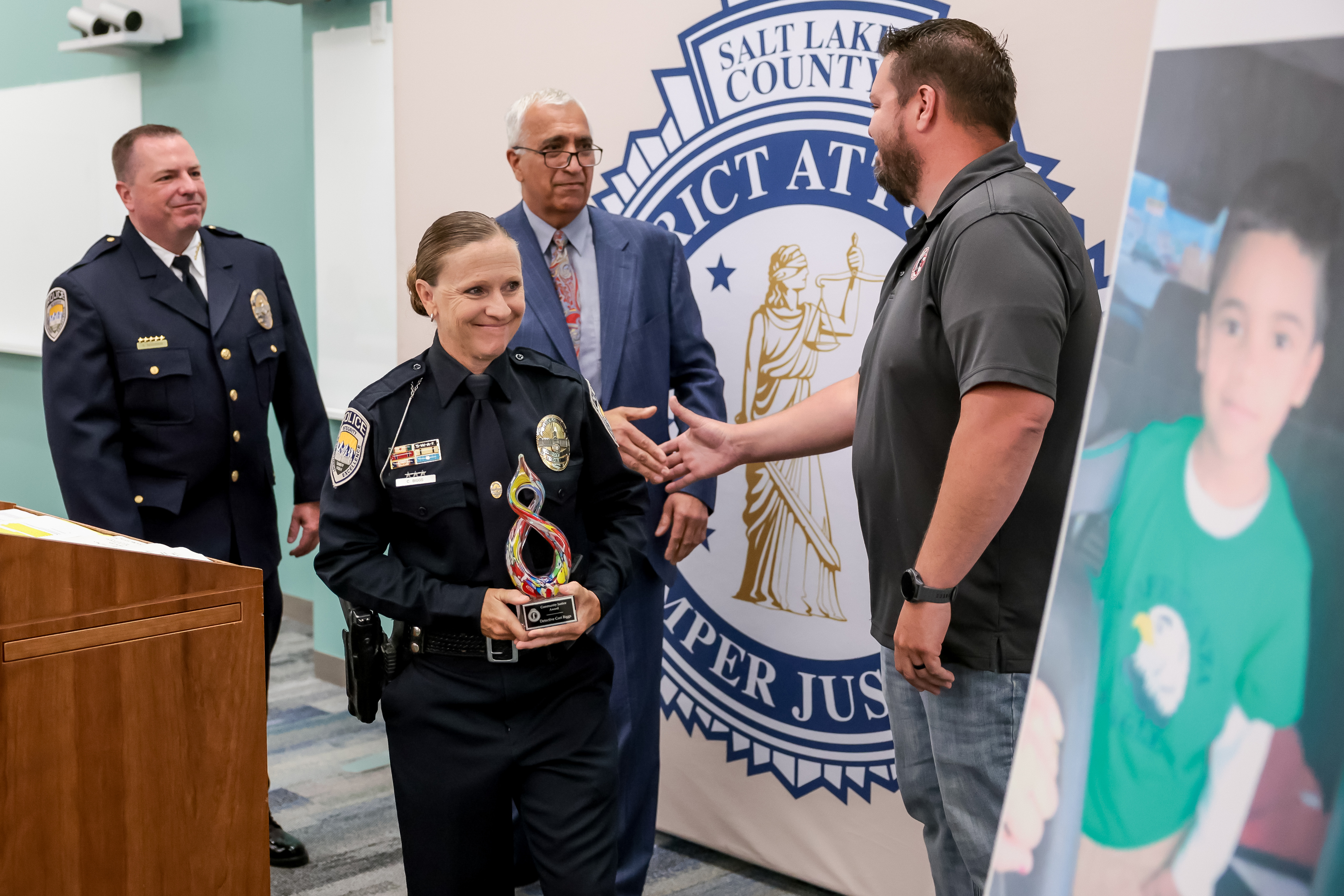Sandy police detective Cori Biggs looks at a photo of 6-year-old Norlin Cruz after receiving the Community Justice Award from Salt Lake County District Attorney Sim Gill at the District Attorney's Office in Salt Lake City on Thursday.