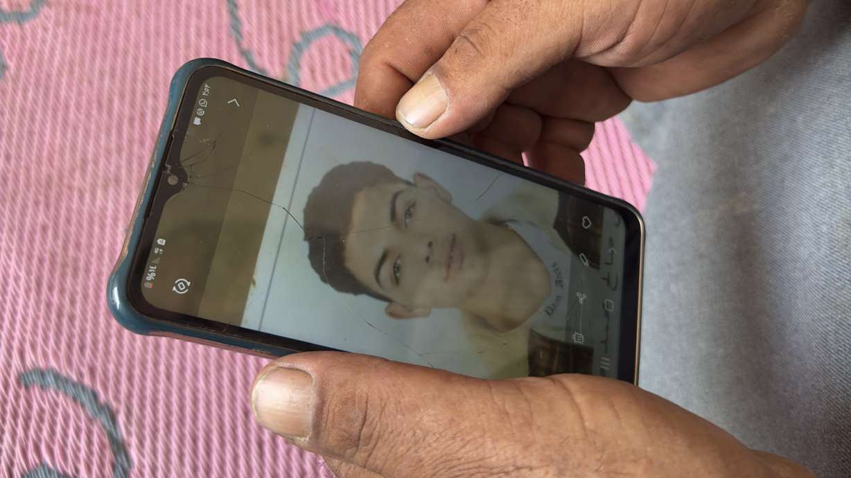 Mohammed Saleh, the father of 18-year-old Yahia Saleh, holds a phone with a photo of his son at home in Ibrash, Egypt, June 18. Yahia is one of dozens from the village feared to have drowned after a packed fishing vessel sank off Greece on June 14.