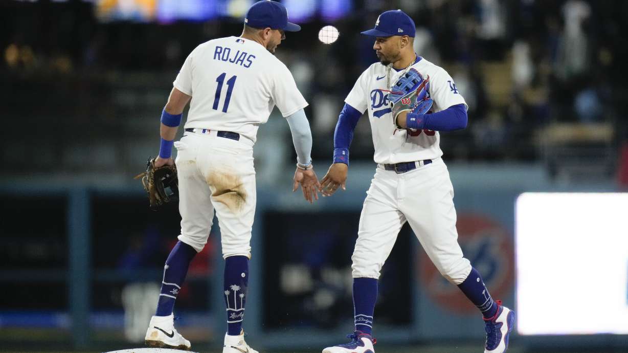 Los Angeles Dodgers' Miguel Rojas (11) and Mookie Betts celebrate the team's win against the Houston Astros in a baseball game Friday, June 23, 2023, in Los Angeles.