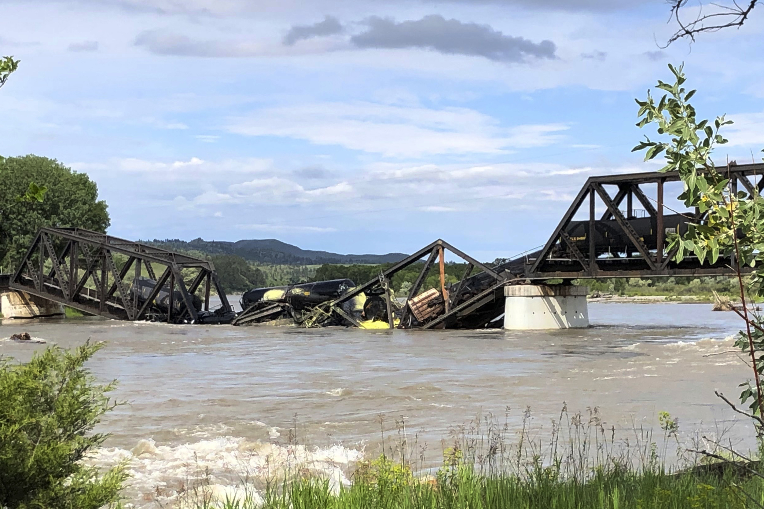 Several train cars are immersed in the Yellowstone River after a bridge collapse near Columbus, Montana, on Saturday. The bridge collapsed overnight, causing a train that was traveling over it to plunge into the water below.