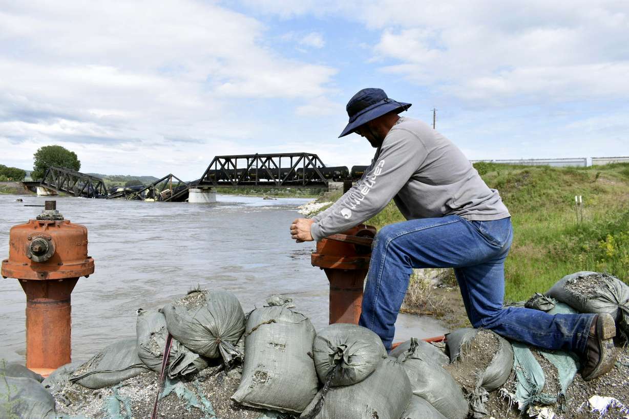 Kelly Hitchcock closes an irrigation ditch just downriver from a bridge collapse at the Yellowstone River near Columbus, Montana on Saturday. The bridge collapsed overnight, causing a train that was traveling over it to plunge into the water below.