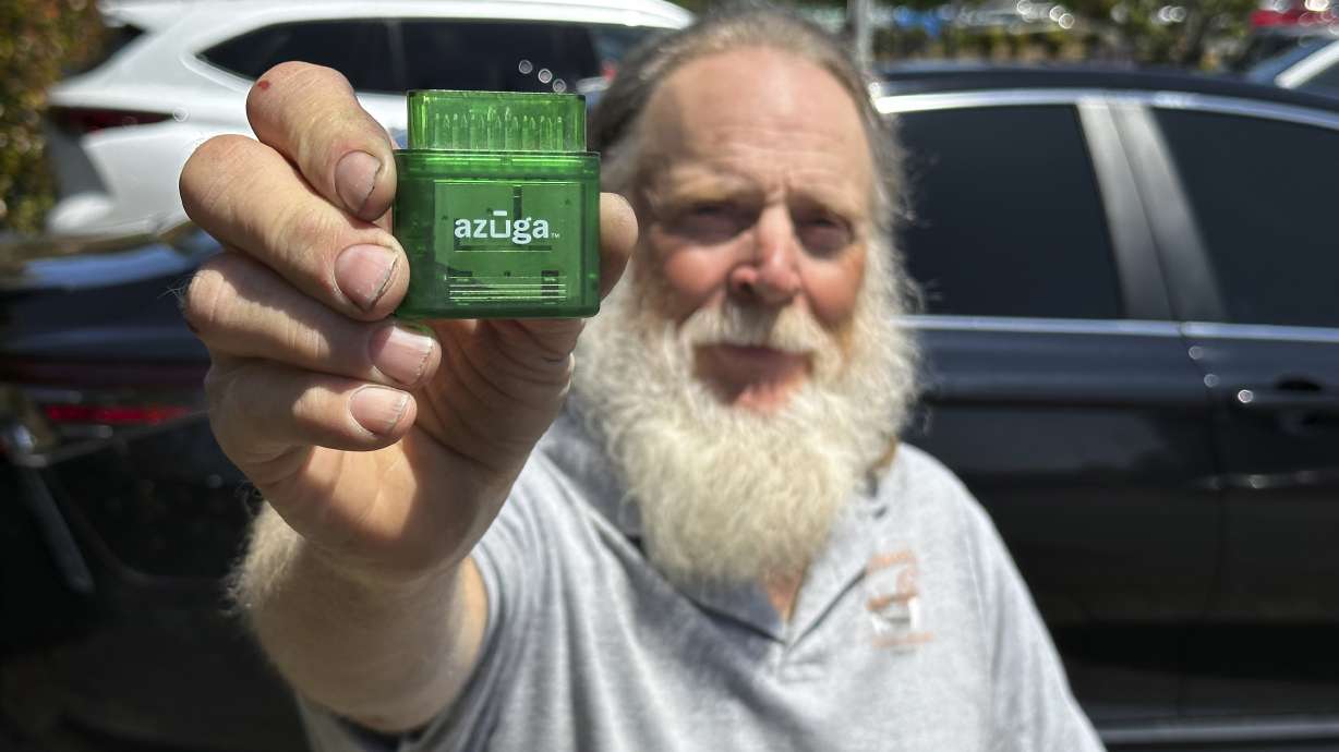Evan Burroughs, who touts an Oregon pilot program that charges motorists by the distance, displays a tracking device the program uses, in Salem, Oregon, on June 21. U.S. states are experimenting with road usage charging programs.
