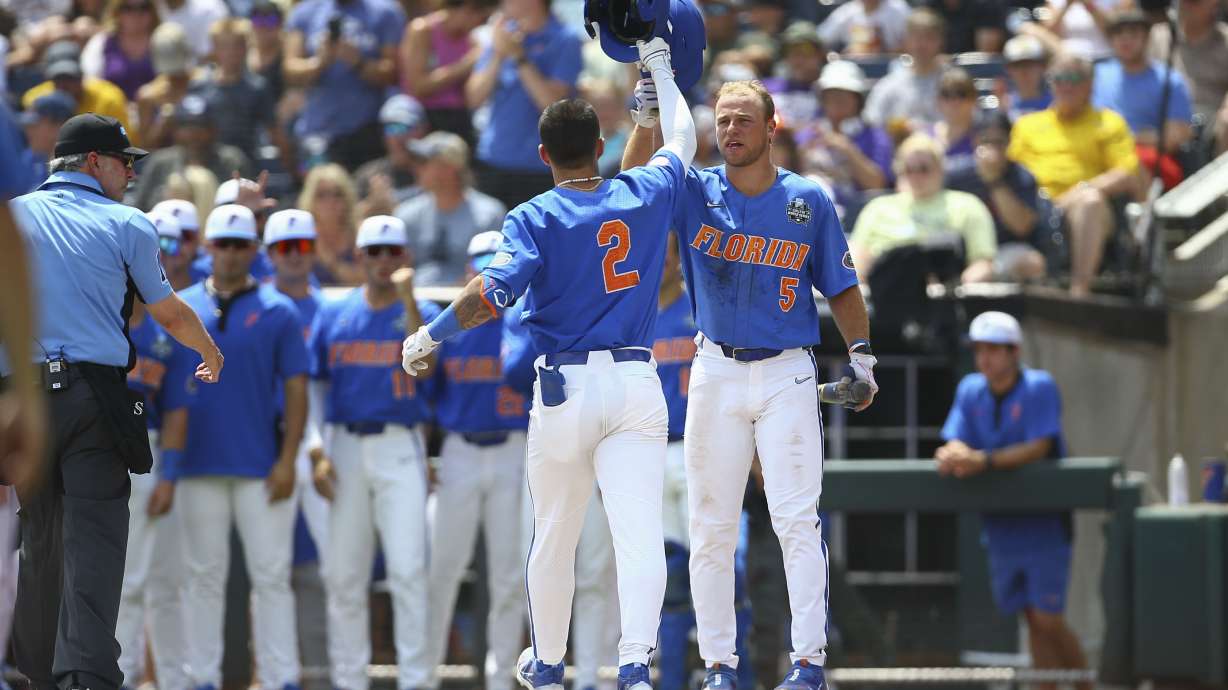 Florida outfielder Ty Evans (2) is greeted at the plate by Ben Nippolt (5) after his solo home run during the second inning of Game 2 of the NCAA College World Series baseball finals against LSU in Omaha, Neb., Sunday, June 25, 2023.