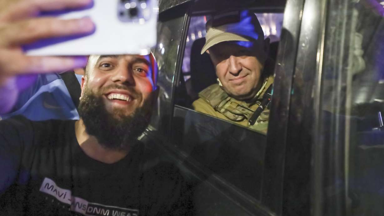 Yevgeny Prigozhin, the owner of the Wagner Group military company, right, sits inside a military vehicle posing for a selfie photo with a local civilian on a street in Rostov-on-Don, Russia, Saturday, prior to leaving an area of the headquarters of the Southern Military District.
