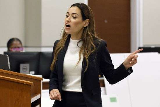 Assistant State Attorney Kristen Gomes motions to the defendant as she gives her closing argument in the trial of former Marjory Stoneman Douglas High School School Resource Officer Scot Peterson, Monday, at the Broward County Courthouse in Fort Lauderdale, Fla. Peterson is accused of failing to confront the shooter who murdered 14 students and three staff members at a Parkland high school five years ago.