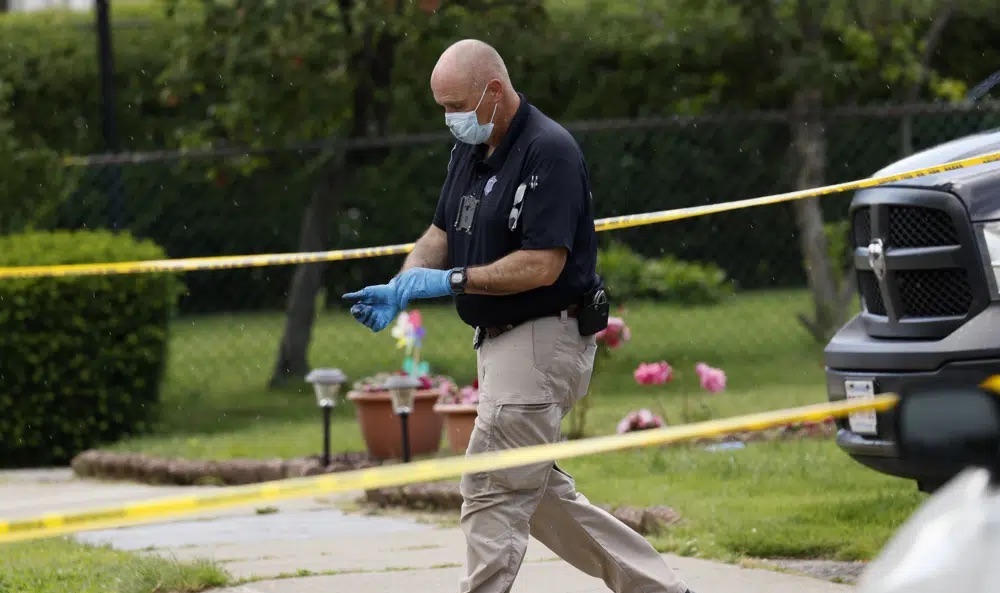 An investigator walks out of a home along Broadway Street, Sunday, in Newton, Mass. A couple celebrating their 50th wedding anniversary and a family member were stabbed to death in what law enforcement officials said was likely a random attack. 