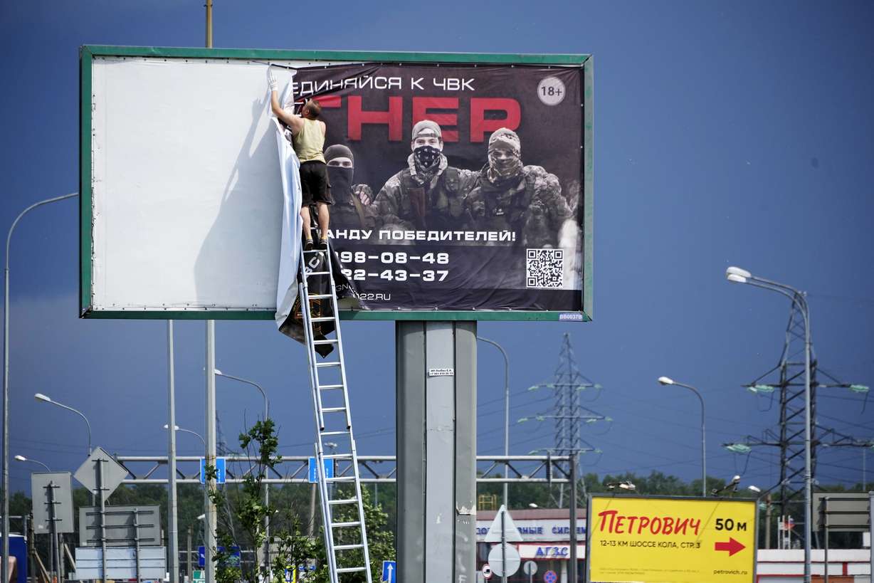 A man takes down the poster with writing reading "Join us at Wagner," which is associated with the owner of the Wagner private military contractor, Yevgeny Prigozhin, is seen above a highway on the outskirts of St. Petersburg, Russia, Saturday.