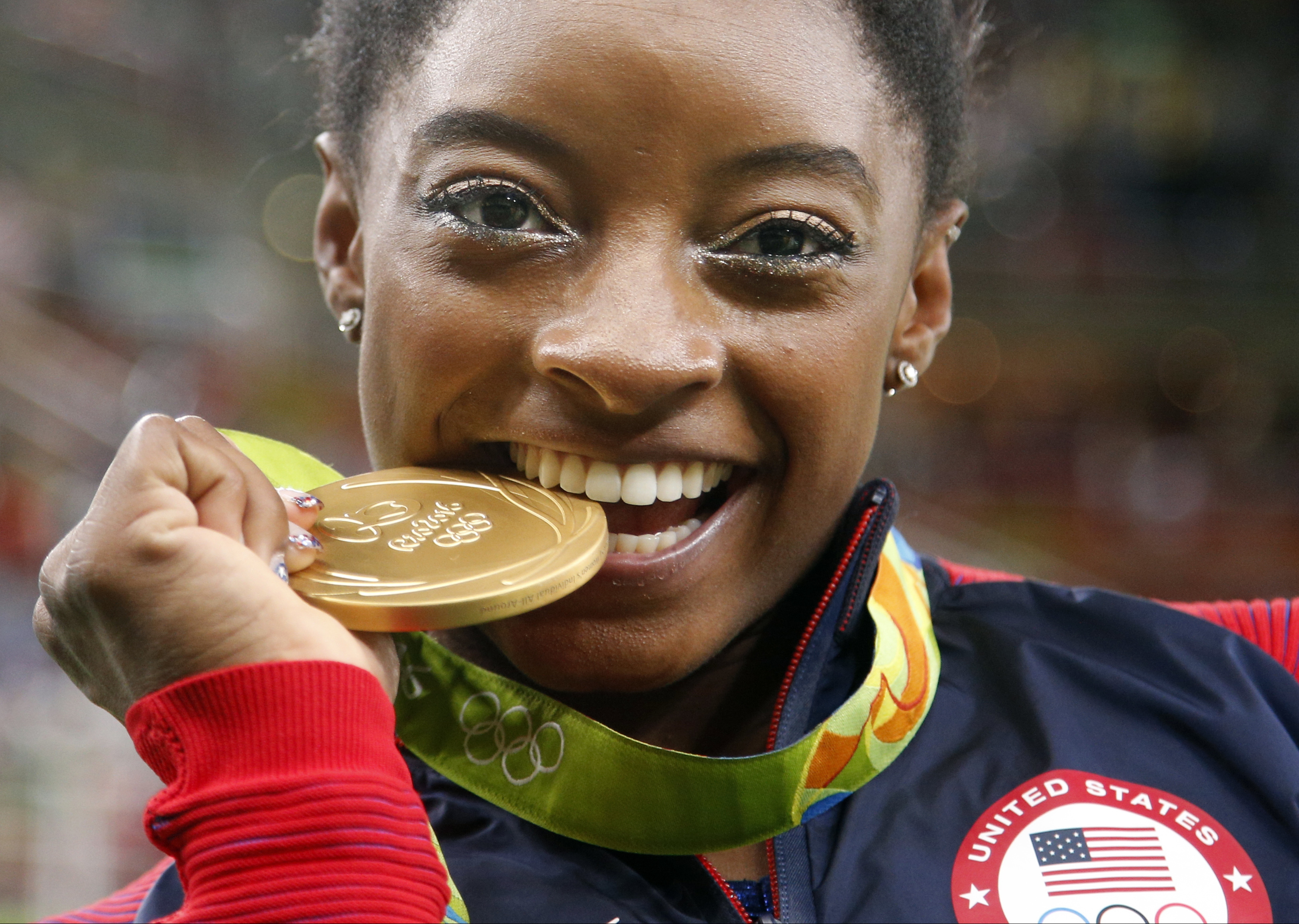 FILE - United States' Simone Biles bites her gold medal for the artistic gymnastics women's individual all-around final at the 2016 Summer Olympics in Rio de Janeiro, Brazil, Aug. 11, 2016. USA Gymnastics announced Wednesday, June 28, 2023, that Biles, the 2016 Olympic champion, will be part of the field at the U.S. Classic outside of Chicago on Aug. 5. The meet will be Biles' first since the 2020 Olympics. 
