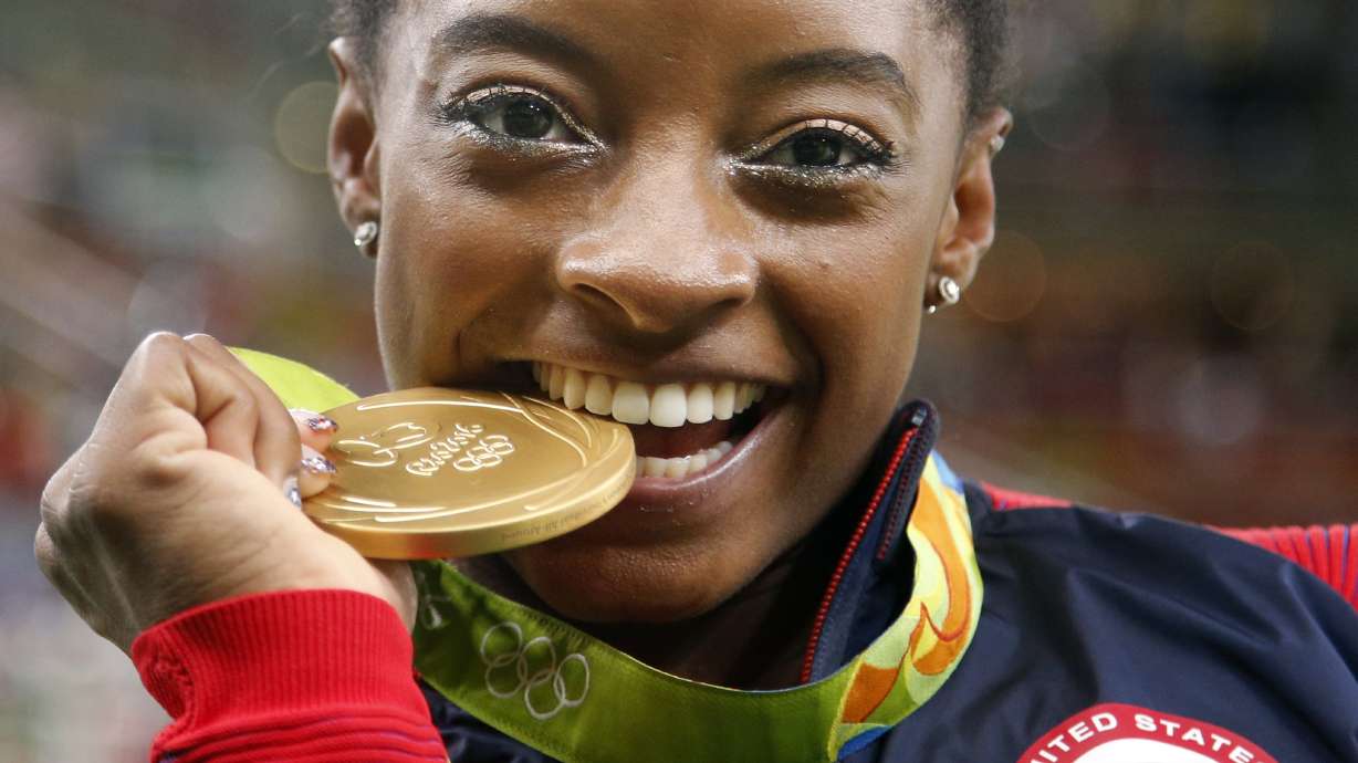 FILE - United States' Simone Biles bites her gold medal for the artistic gymnastics women's individual all-around final at the 2016 Summer Olympics in Rio de Janeiro, Brazil, Aug. 11, 2016. USA Gymnastics announced Wednesday, June 28, 2023, that Biles, the 2016 Olympic champion, will be part of the field at the U.S. Classic outside of Chicago on Aug. 5. The meet will be Biles' first since the 2020 Olympics.
