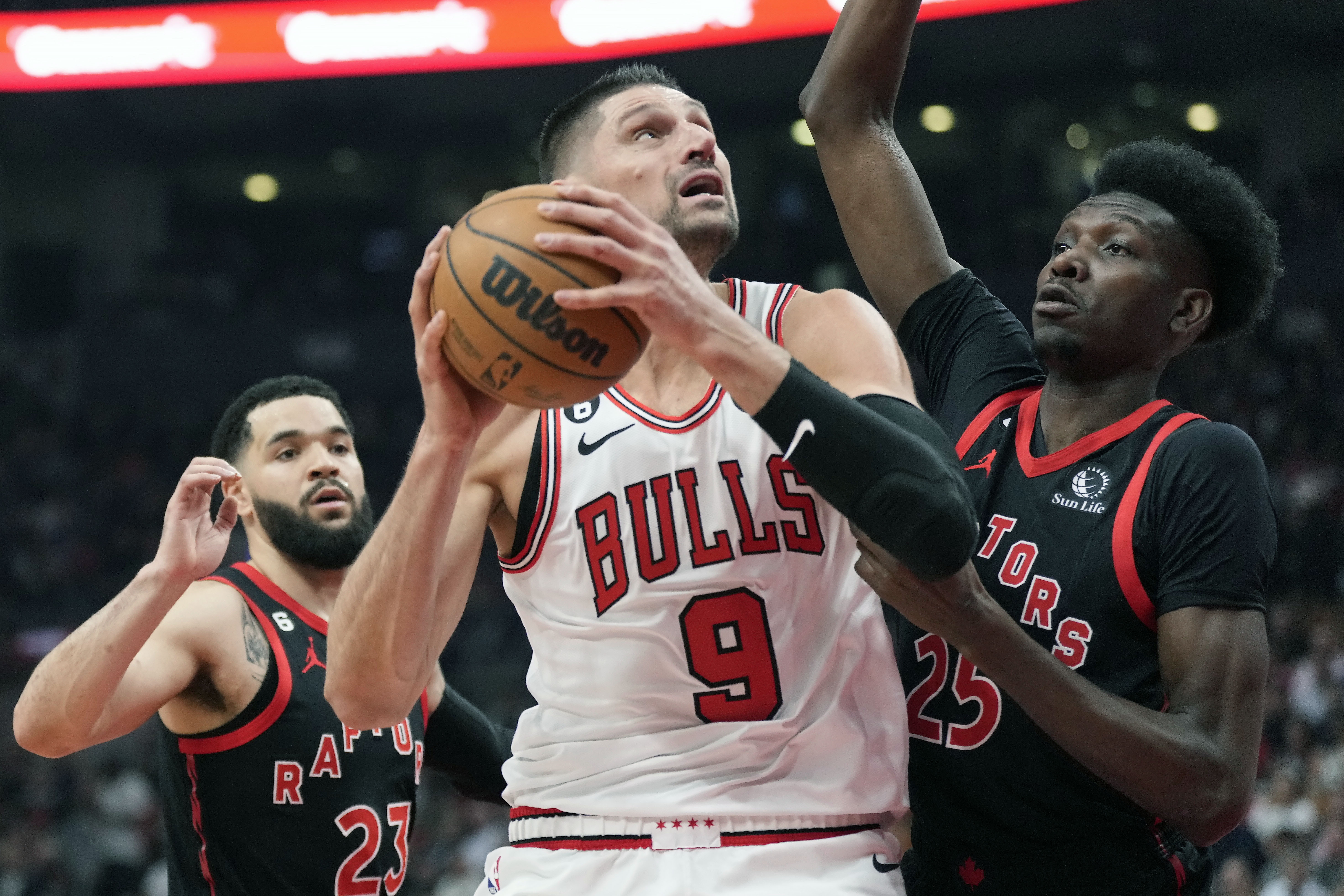FILE - Chicago Bulls center Nikola Vucevic (9) looks toward the basket as Toronto Raptors forward Chris Boucher (25) and guard Fred VanVleet (23) defend during the first half of an NBA basketball play-in tournament game Wednesday, April 12, 2023, in Toronto. The Chicago Bulls and center Nikola Vucevic agreed Wednesday, June 28, 2023 to a $60 million, three-year extension, keeping the two-time All-Star off the free agent market.