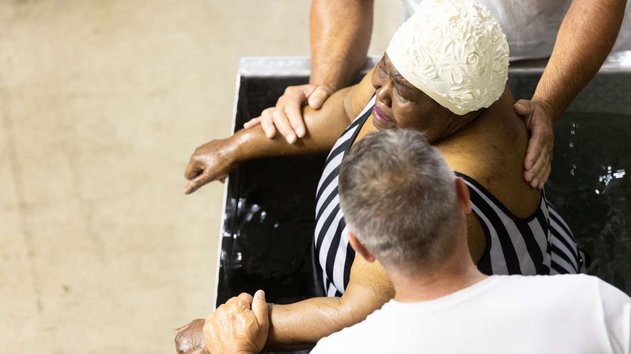 David Verdi, front, and Mike Myers comfort Joanne Jackson after she was baptized at the 2023 Convention of Jehovah’s Witnesses at the Dee Events Center in Ogden on Saturday.