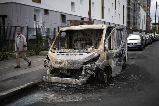 A man walks past a burned van on the aftermath of protests in Colombes, outside Paris, Saturday. The fatal shooting of Nahel Merzouk, whose last name has not been made public, stirred up long-simmering tensions between police and young people in housing projects who struggle with poverty, unemployment and racial discrimination.