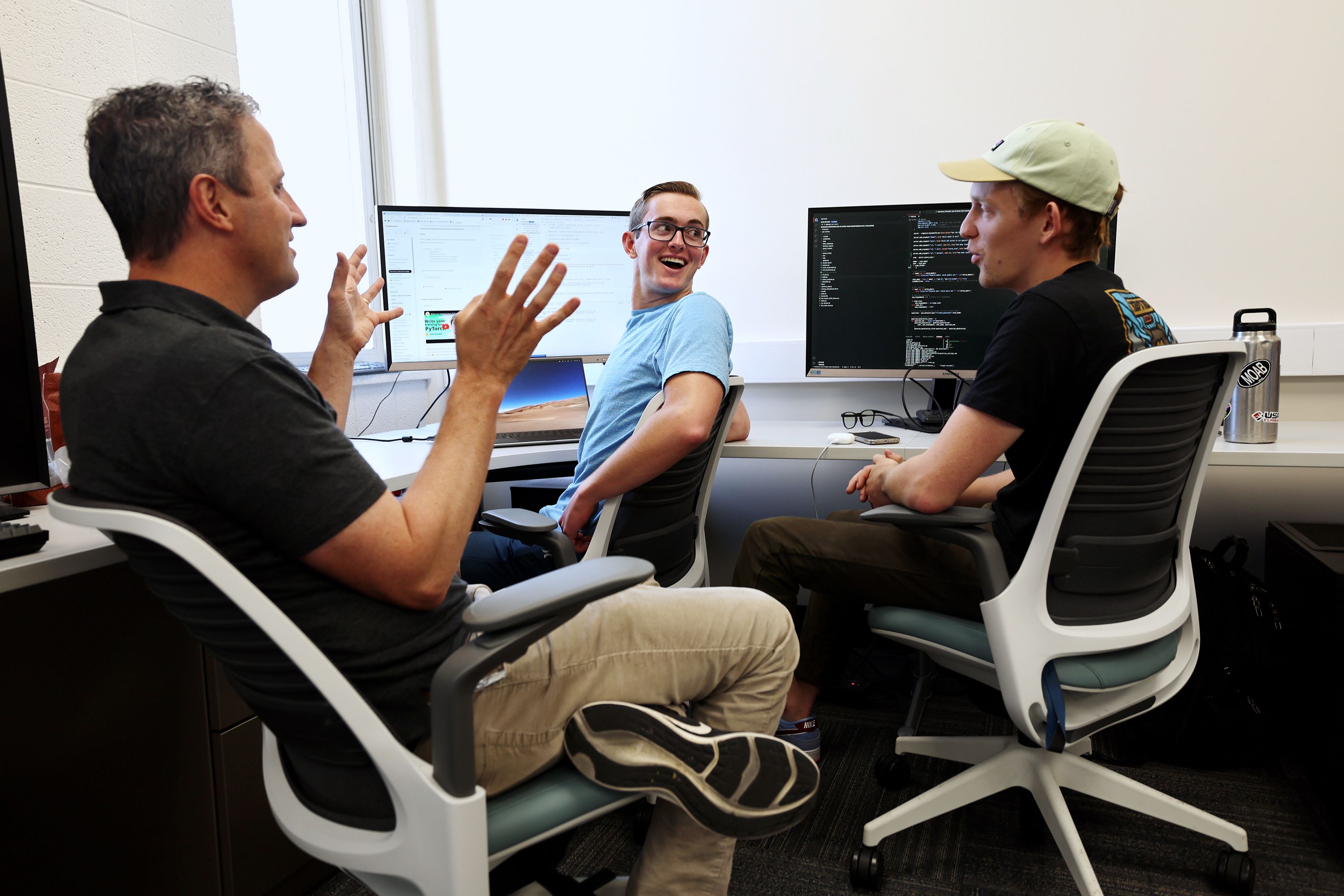 Associate professor David Wingate, left, talks with students BYU students Ben Gubler and Sam Vance as they and others work in the Perception, Control and Cognition lab at BYU on June 30. 