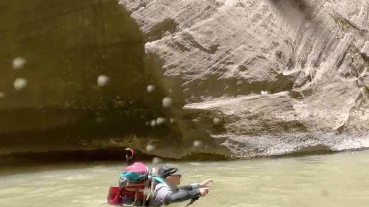 A hiker treks through the Virgin River in the Narrows on Friday. The route reopened on June 19, but Zion National Park rangers say the trail can still be "challenging" because of the current river flows.