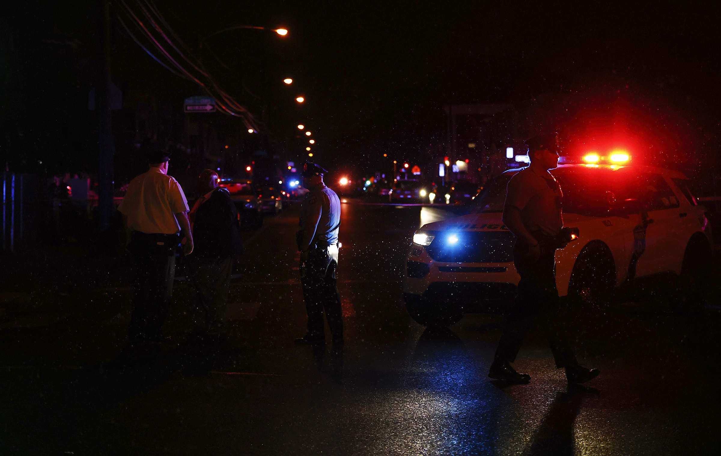 Philadelphia police stand at the intersection of 56th Street and Kingsessing Avenue after multiple people were shot in Southwest Philadelphia, late Monday.