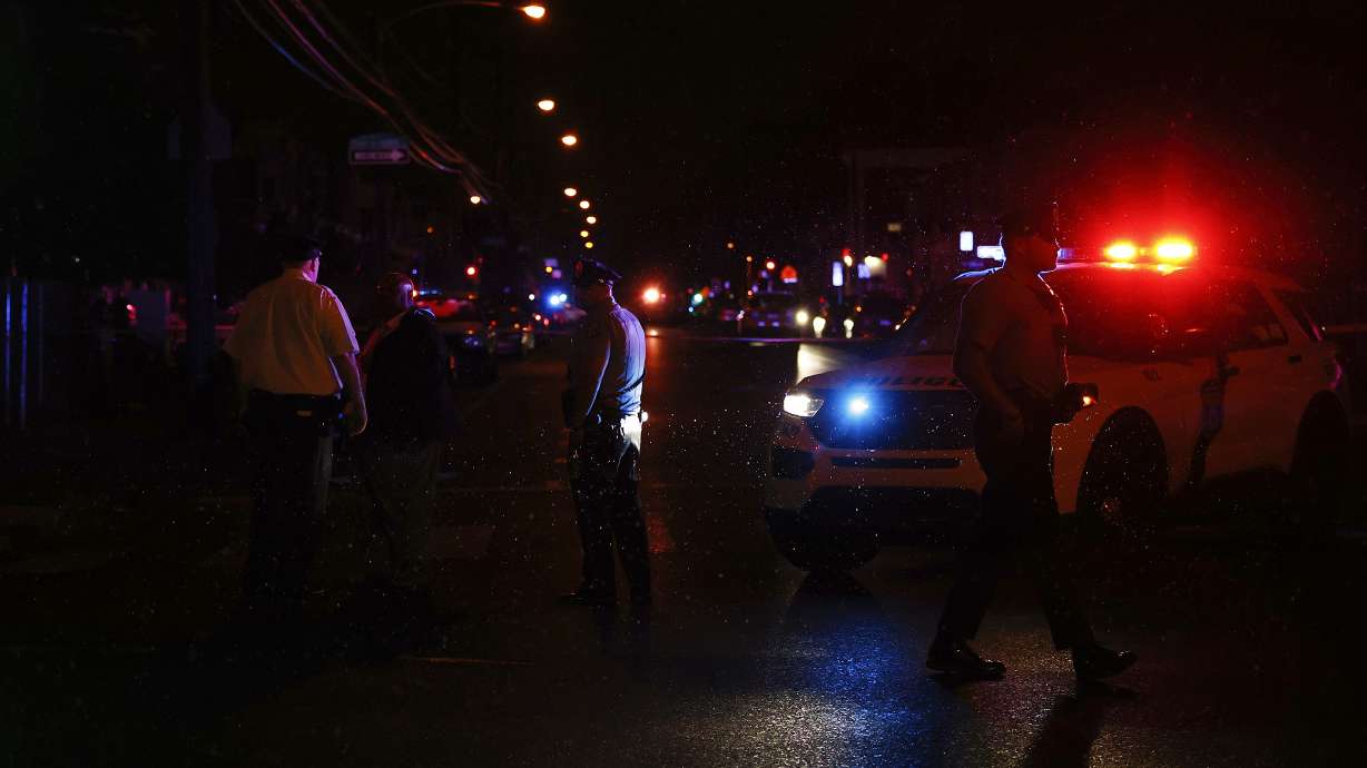 Philadelphia police stand at the intersection of 56th Street and Kingsessing Avenue after multiple people were shot in Southwest Philadelphia, late Monday.