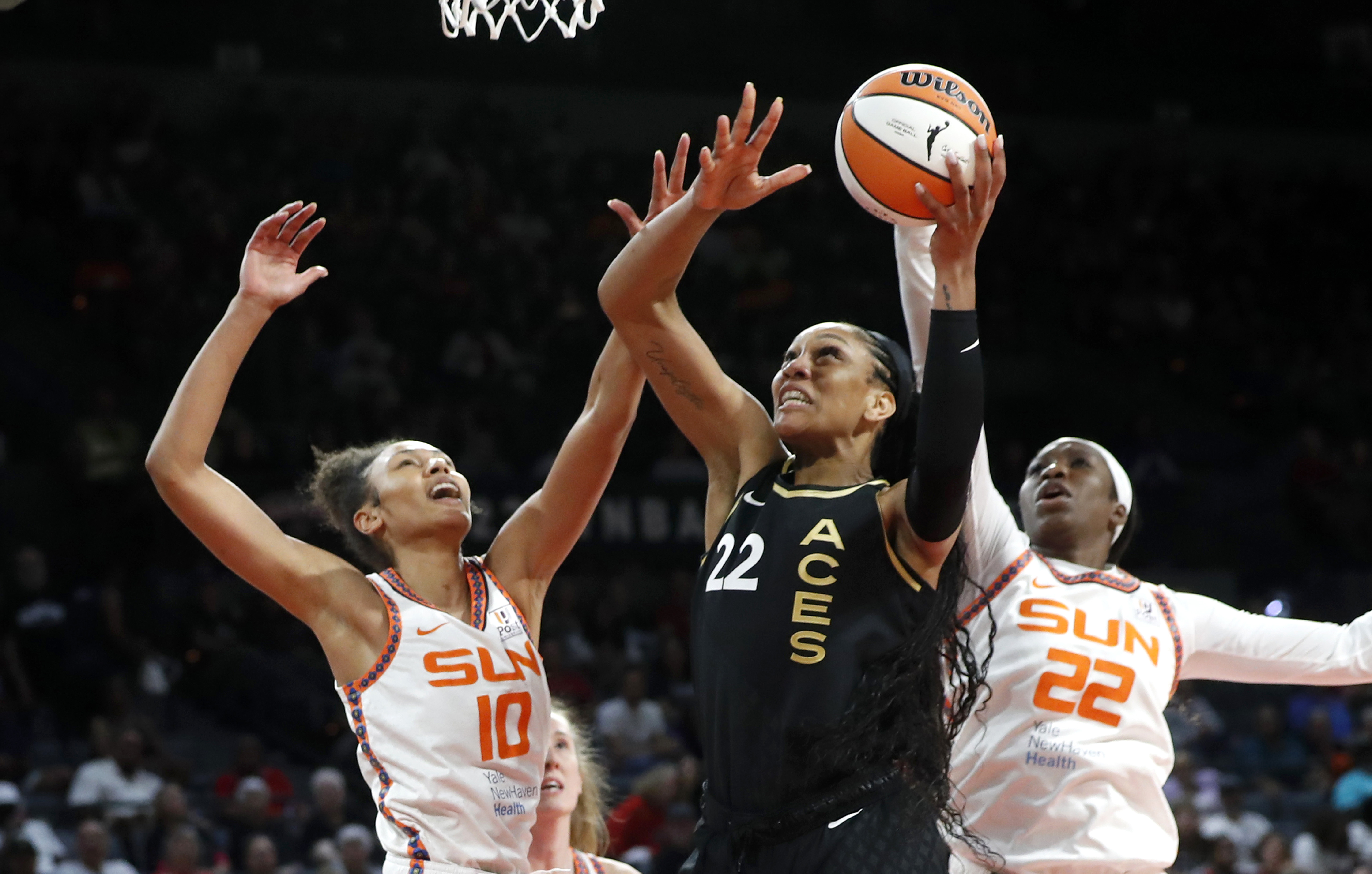 Las Vegas Aces forward A'ja Wilson, center, goes up to shoot between Connecticut Sun forwards Olivia Nelson-Ododa (10) and Liz Dixon, right, during the second half of a WNBA basketball game Saturday, July 1, 2023, in Las Vegas. 