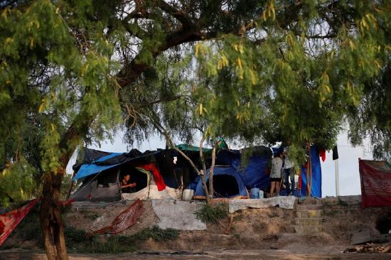 An asylum seeker checks her cellphone inside her tent as she waits to attempt to cross into the U.S. by an appointment through the Customs and Border Protection app, called CBP One, at a makeshift camp, in Matamoros, Mexico, June 21.
