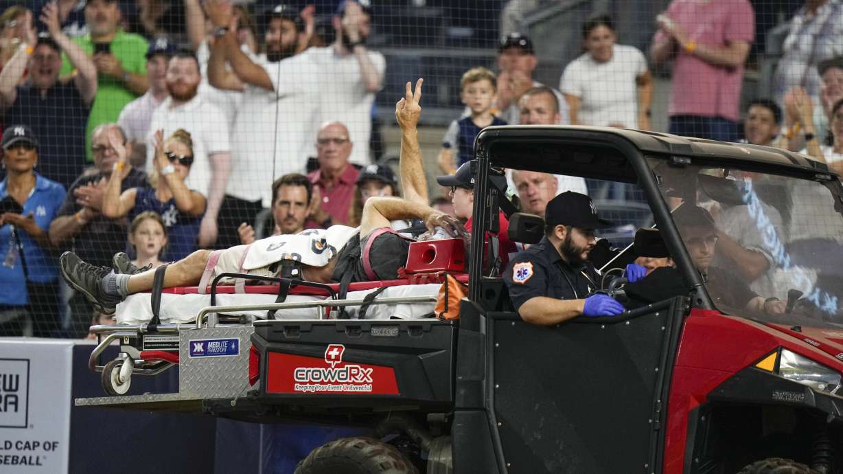 A camera operator who was injured on a throwing error by Baltimore Orioles third baseman Gunnar Henderson gestures to the crowd as he is carted off the field during the fifth inning of the Orioles' baseball game against the New York Yankees on Wednesday, July 5, 2023, in New York.