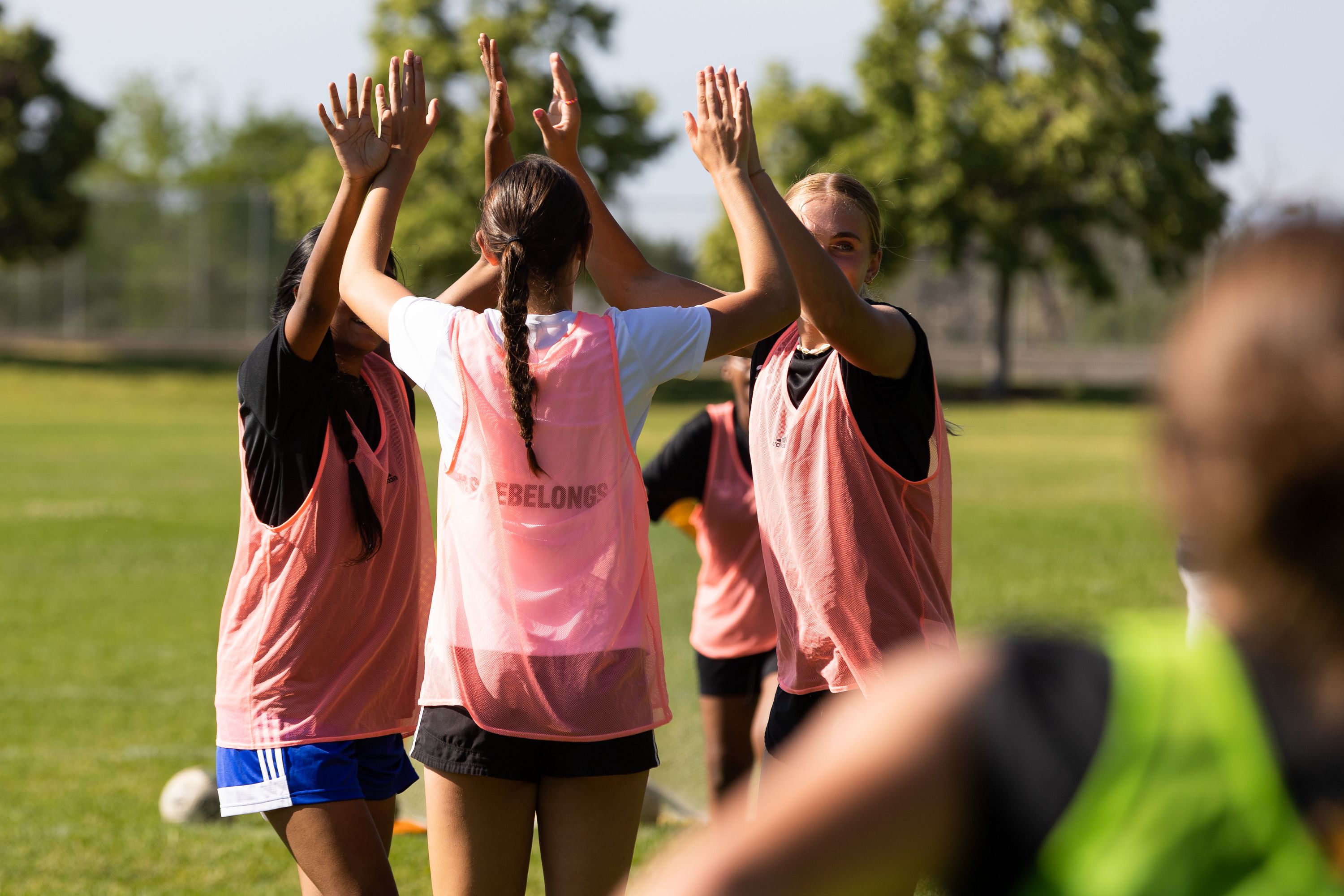 Anu Arumugarasa, of Sri Lanka, left, Sutton Hull, of Park City, and Eliza Collings, of Alpine, high-five at their soccer practice at Lone Peak Park in Sandy on Thursday. #SheBelongs brings together refugee and nonrefugee girls through soccer.