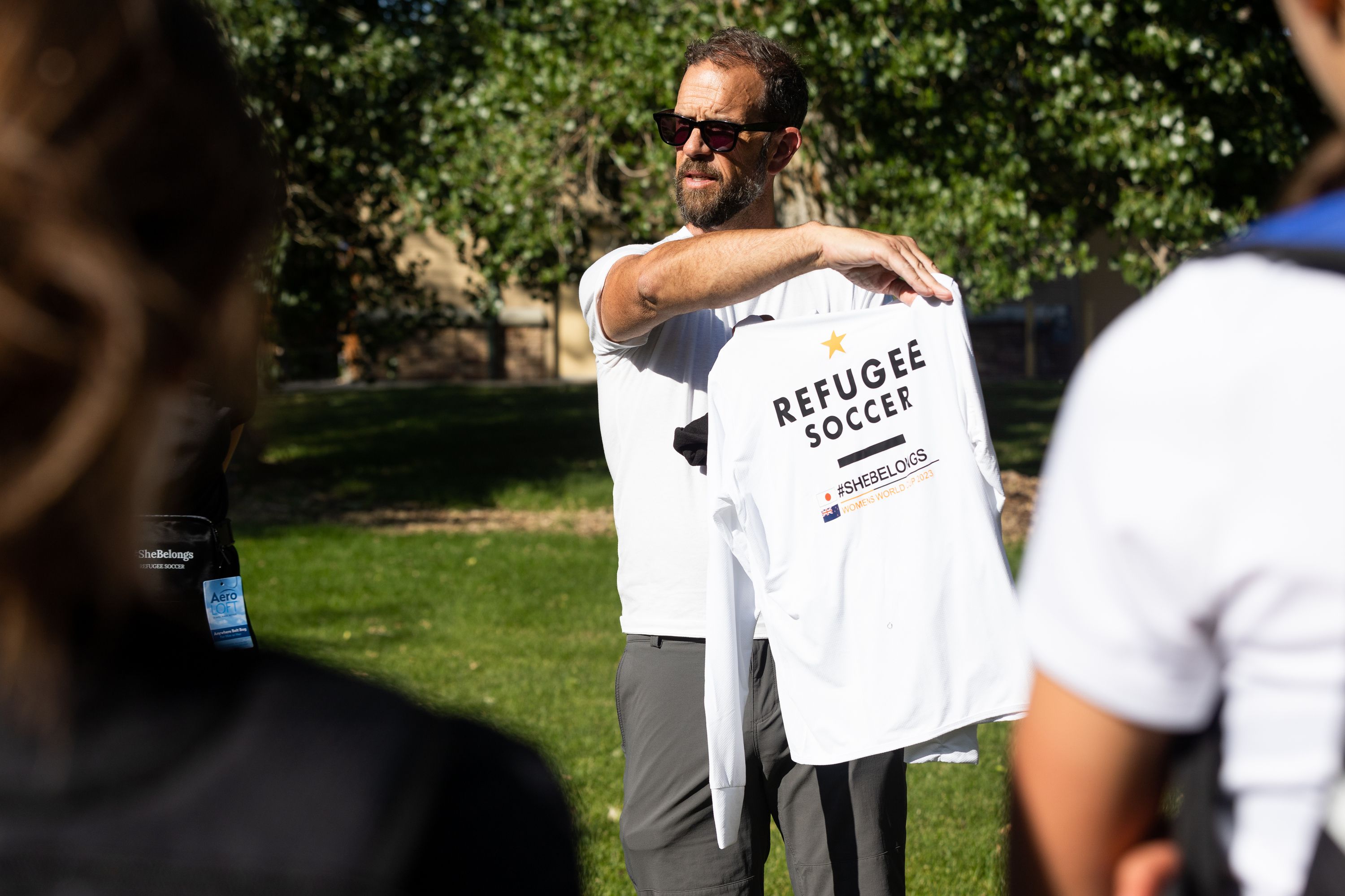 Adam Miles shows the #SheBelongs team members their new gear for traveling to the Women’s World Cup hosted by Australia and New Zealand at Lone Peak Park in Sandy on Thursday. #SheBelongs is a four-month program bringing together refugee and nonrefugee girls through soccer.