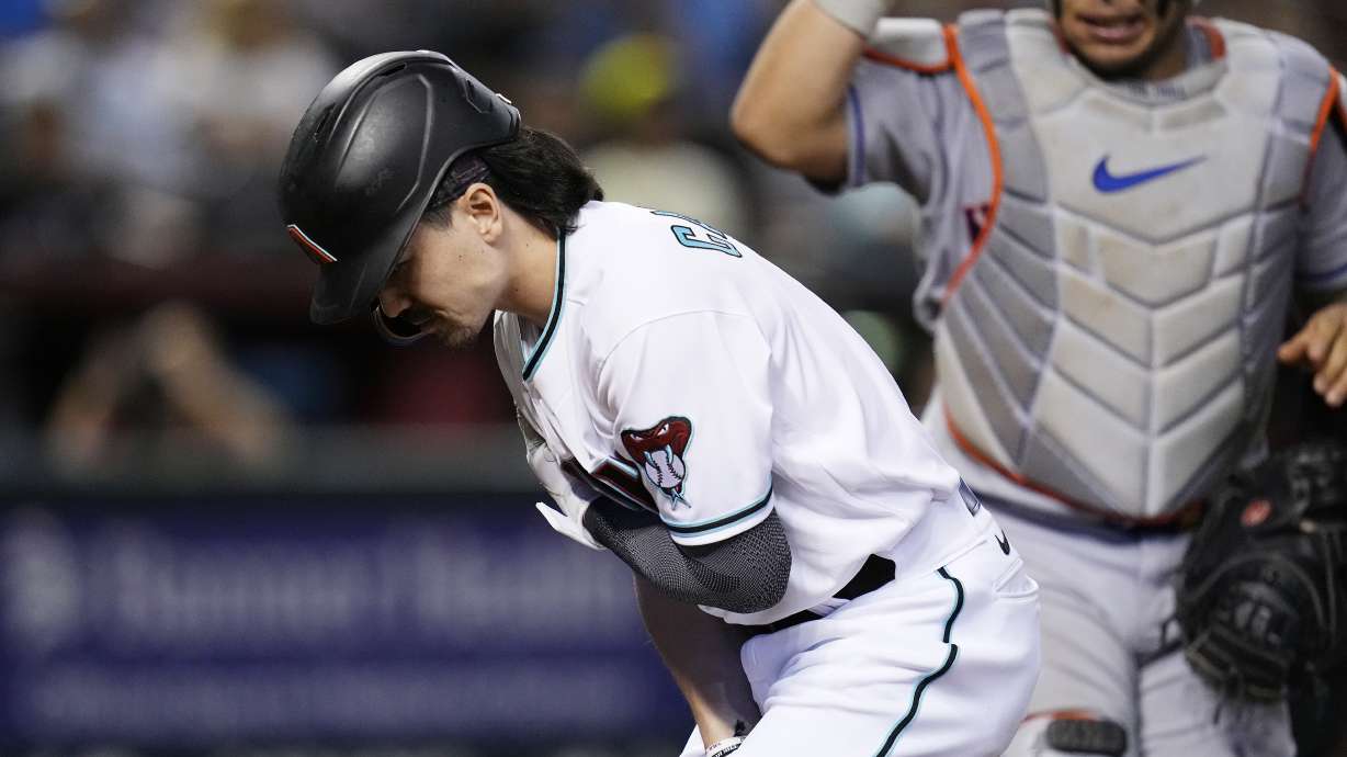 Arizona Diamondbacks' Corbin Carroll, left, holds his shoulder after an injury during a swing attempt, as New York Mets catcher Francisco Alvarez watches during the seventh inning of a baseball game Thursday, July 6, 2023, in Phoenix.