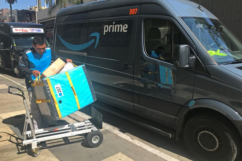 An Amazon worker loads a trolley from a Prime delivery van in Los Angeles, Feb. 25, 2019. Amazon.com hopes to tempt U.S. shoppers on Tuesday to open inflation-thinned wallets by offering deeper discounts on a wide range of goods and services.