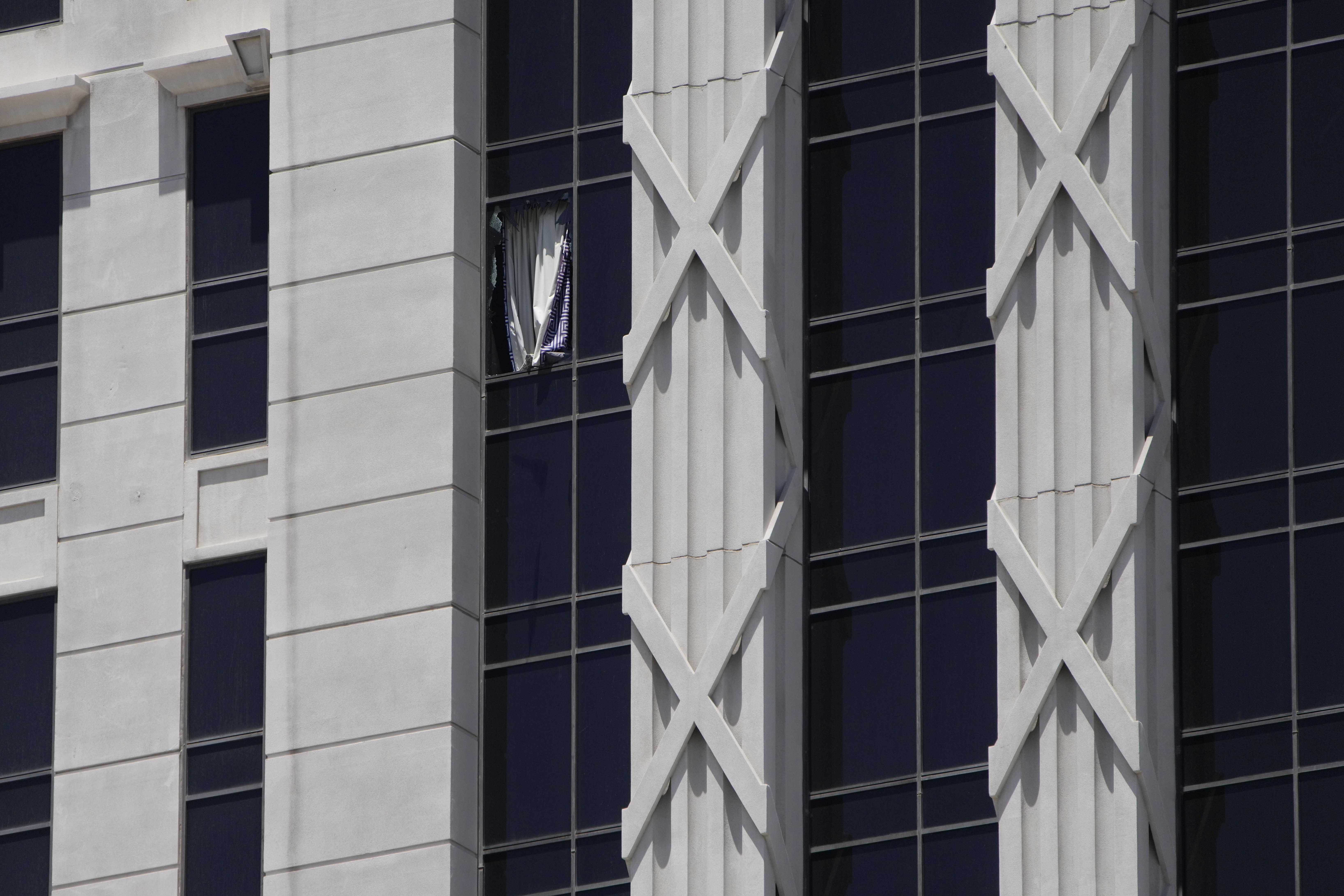 A curtain hangs out of a broken window on a hotel tower at Caesars Palace Hotel & Casino, Tuesday in Las Vegas. Las Vegas police say a man has taken a woman hostage at the Caesars Palace Hotel & Casino.